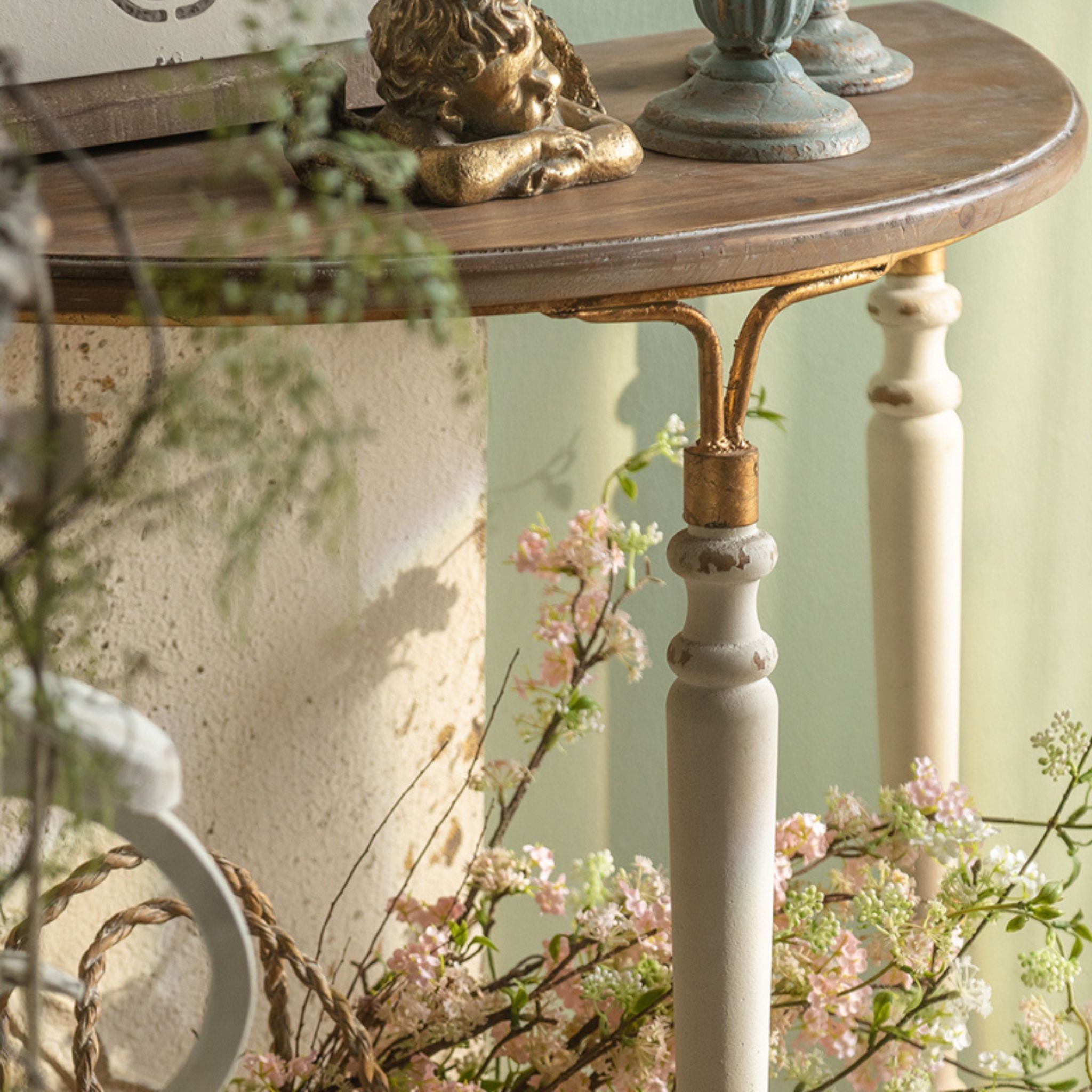 Close-up of the Estelle console showing the gold-leaf iron arch where the leg meets the timber top.