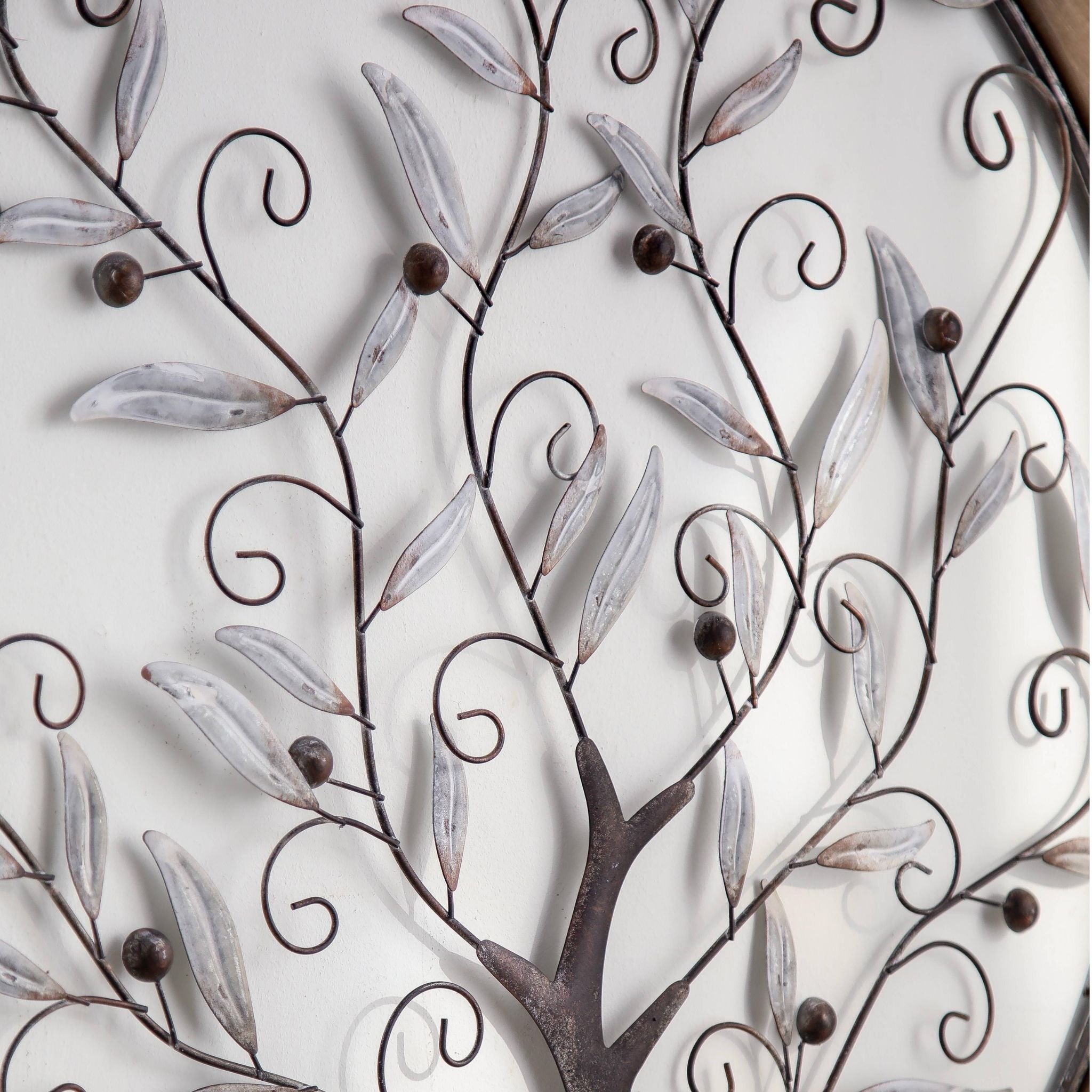 Close view of the whitewashed metal leaves, scrolled branches and rust-toned berries on the tree of life