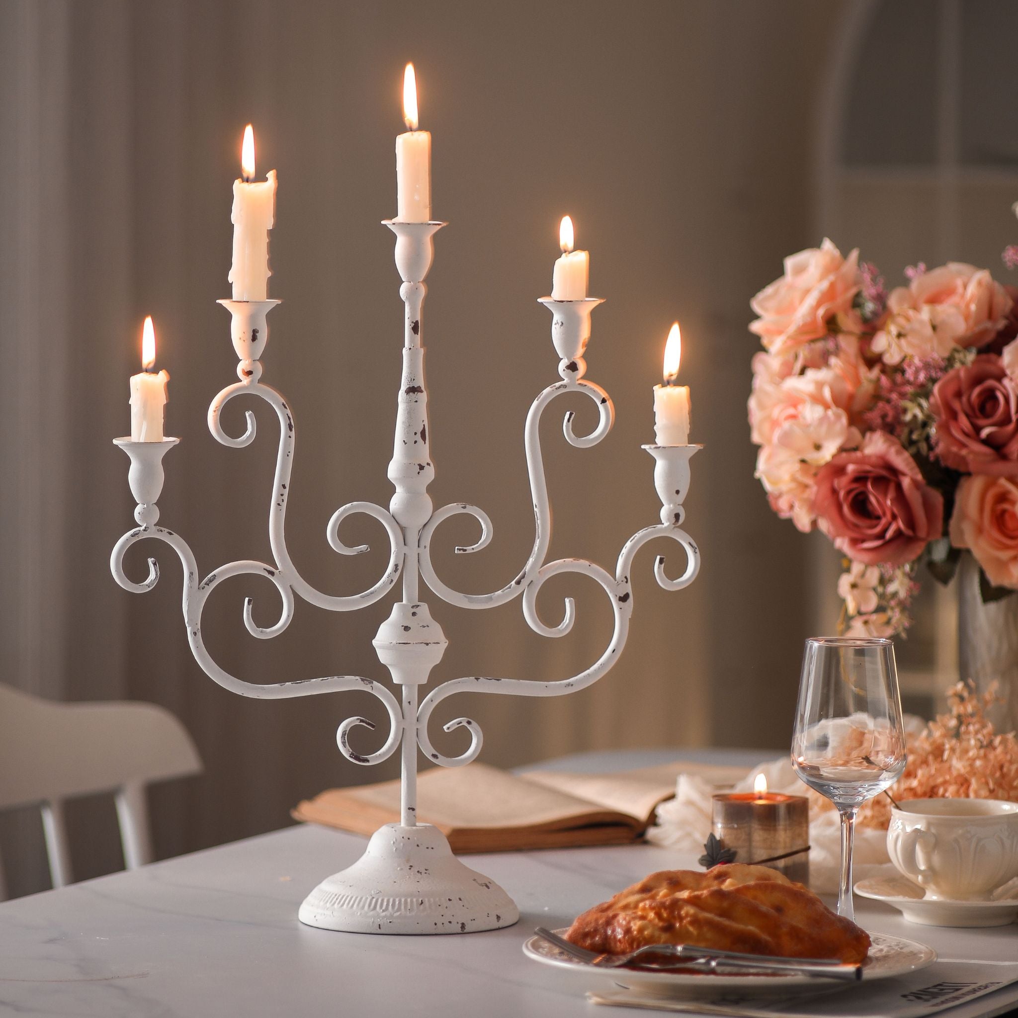 Chloe distressed white five-arm candelabra lit with five taper candles on a dining table. Hero.