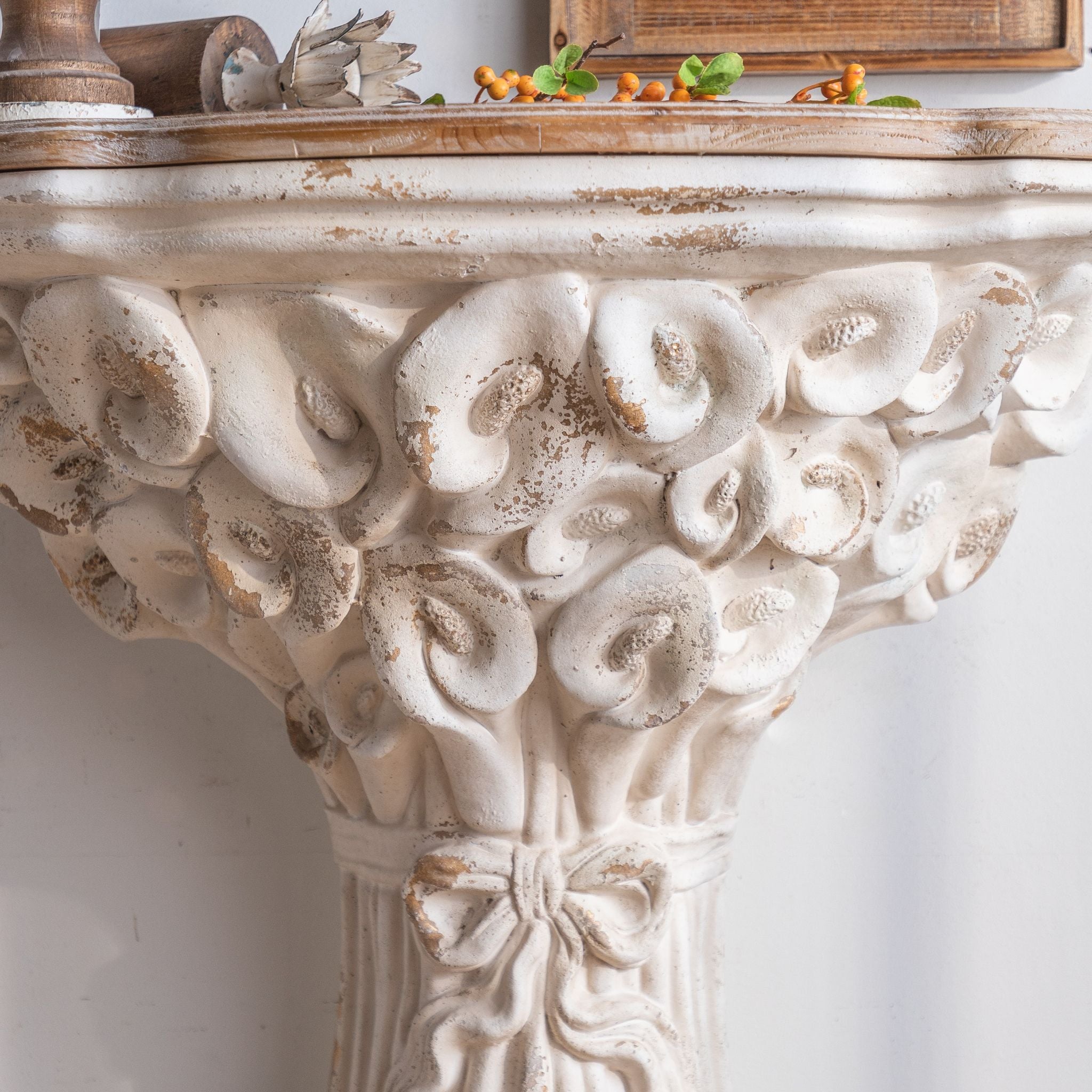 Close-up of the carved calla lily bouquet under the timber top of the Celestine console