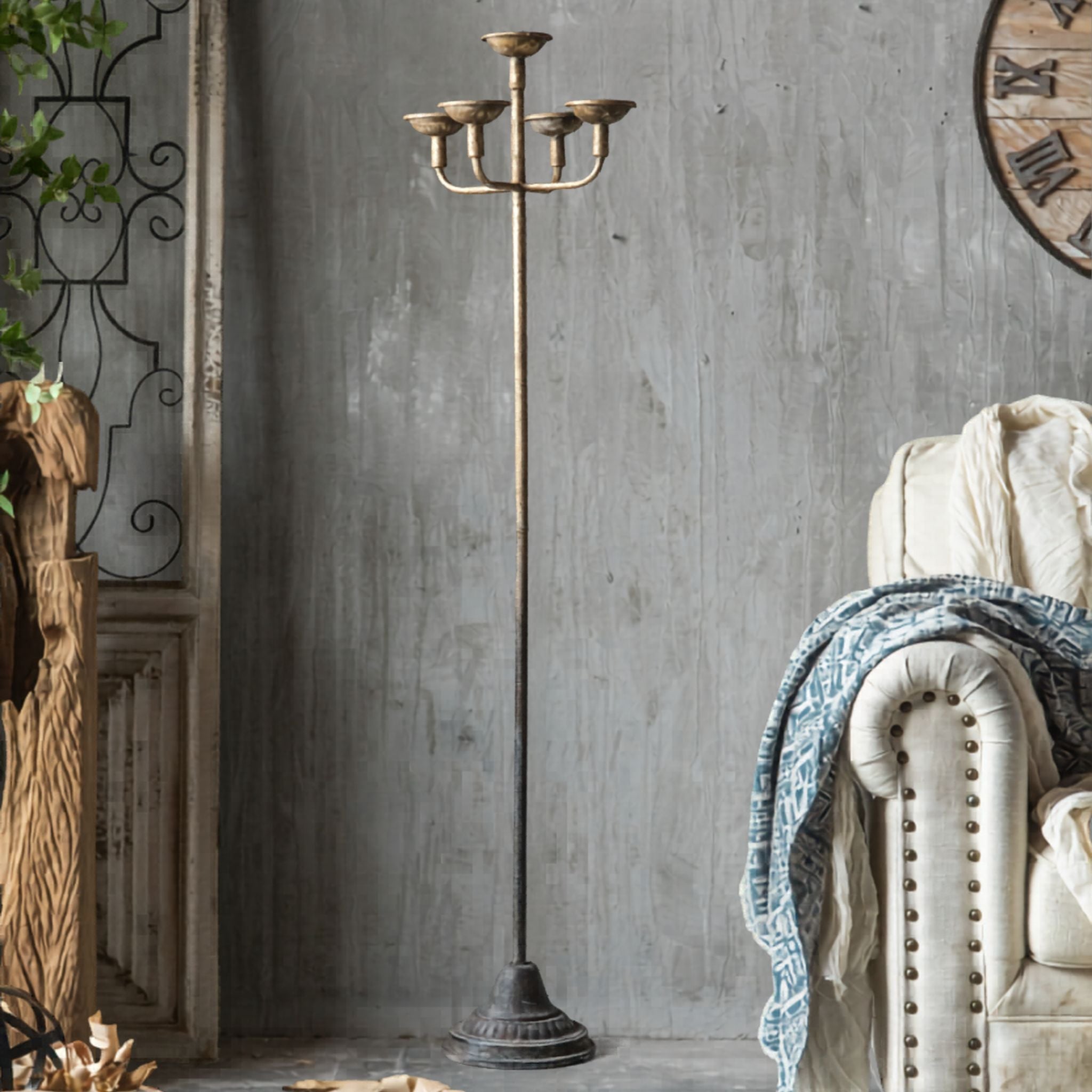 Florence French Provincial floor standing candelabra in antique gold aged metal, five-cup head on a slender stem and moulded base, 149cm, styled beside an armchair. Hero.