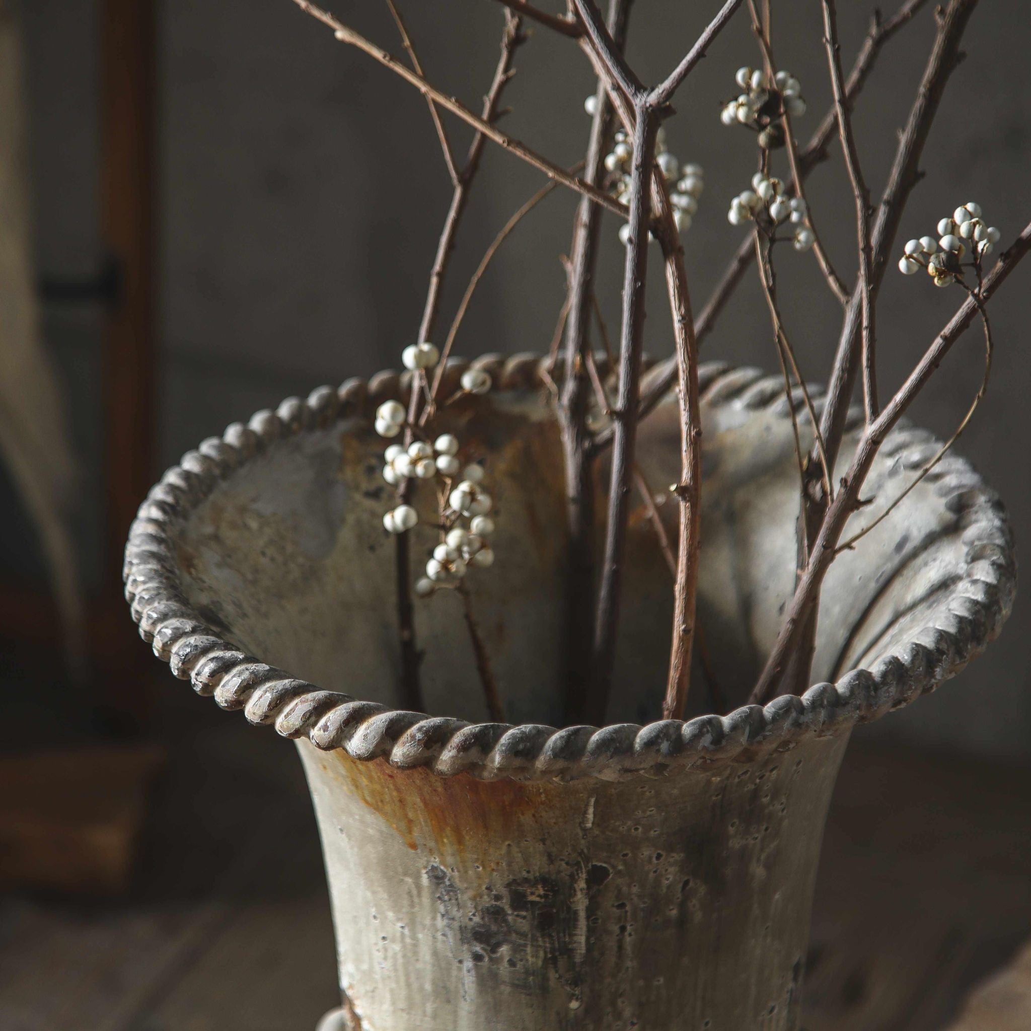 Florent close-up of the rope-twist rim and flared bowl, weathered grey with rust bleed.