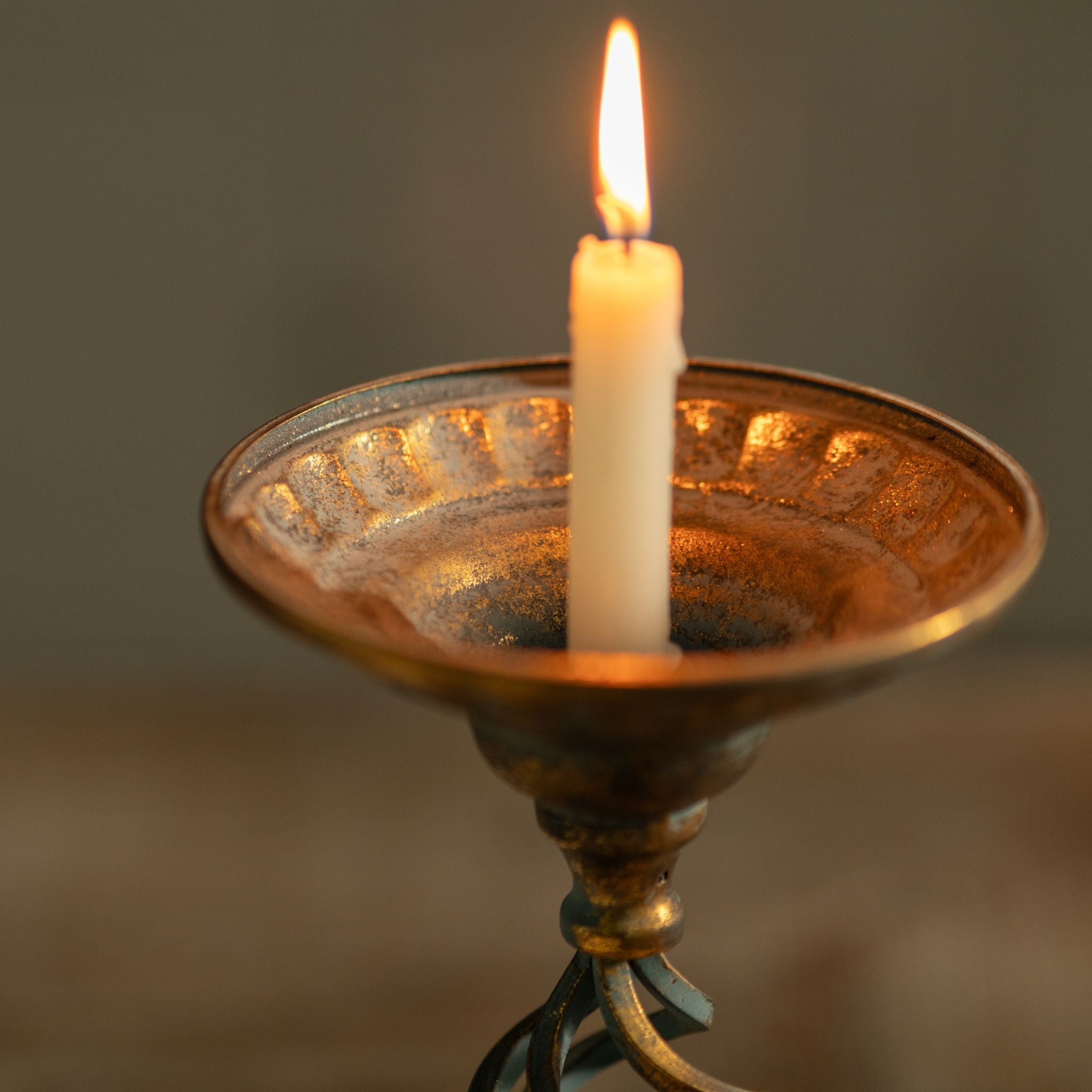 Close-up of the Francis dished top with beaded under-rim and warm gold-washed interior holding a taper.