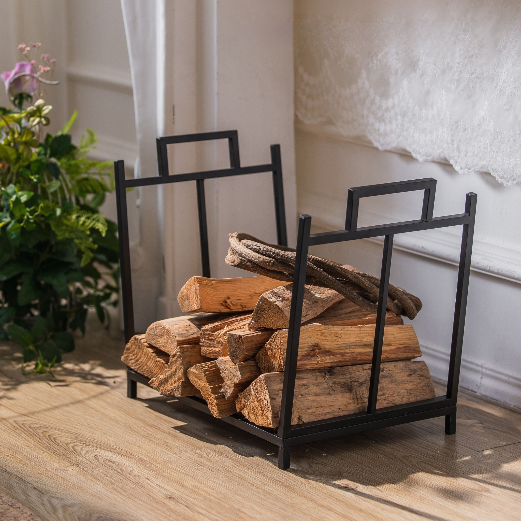 Gaultier low matte black firewood log holder with cut-out carry handles, loaded with split logs.