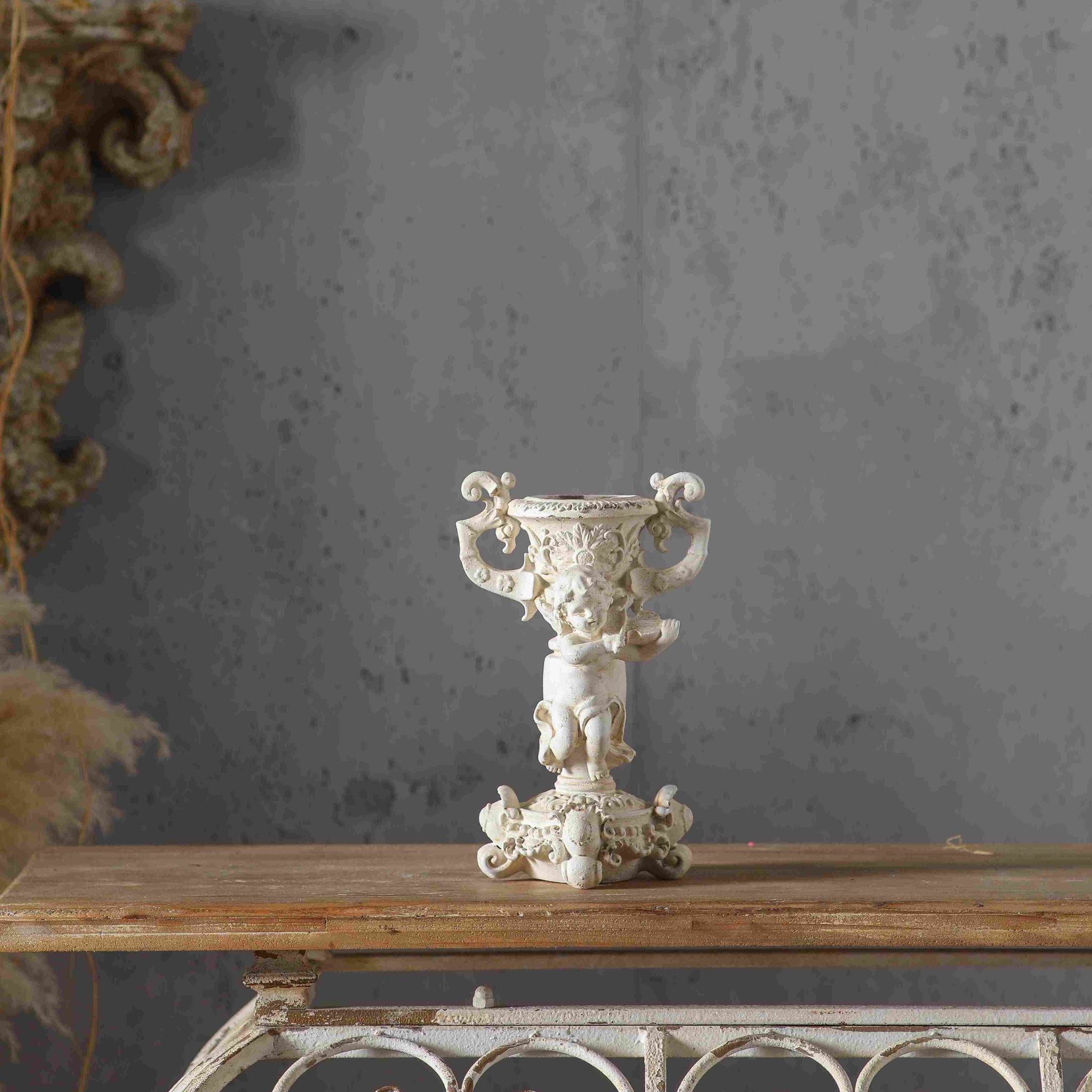 Jean Paul French Provincial cherub candle holder in antique cream, a putto holding a tambourine beneath an urn candle cup