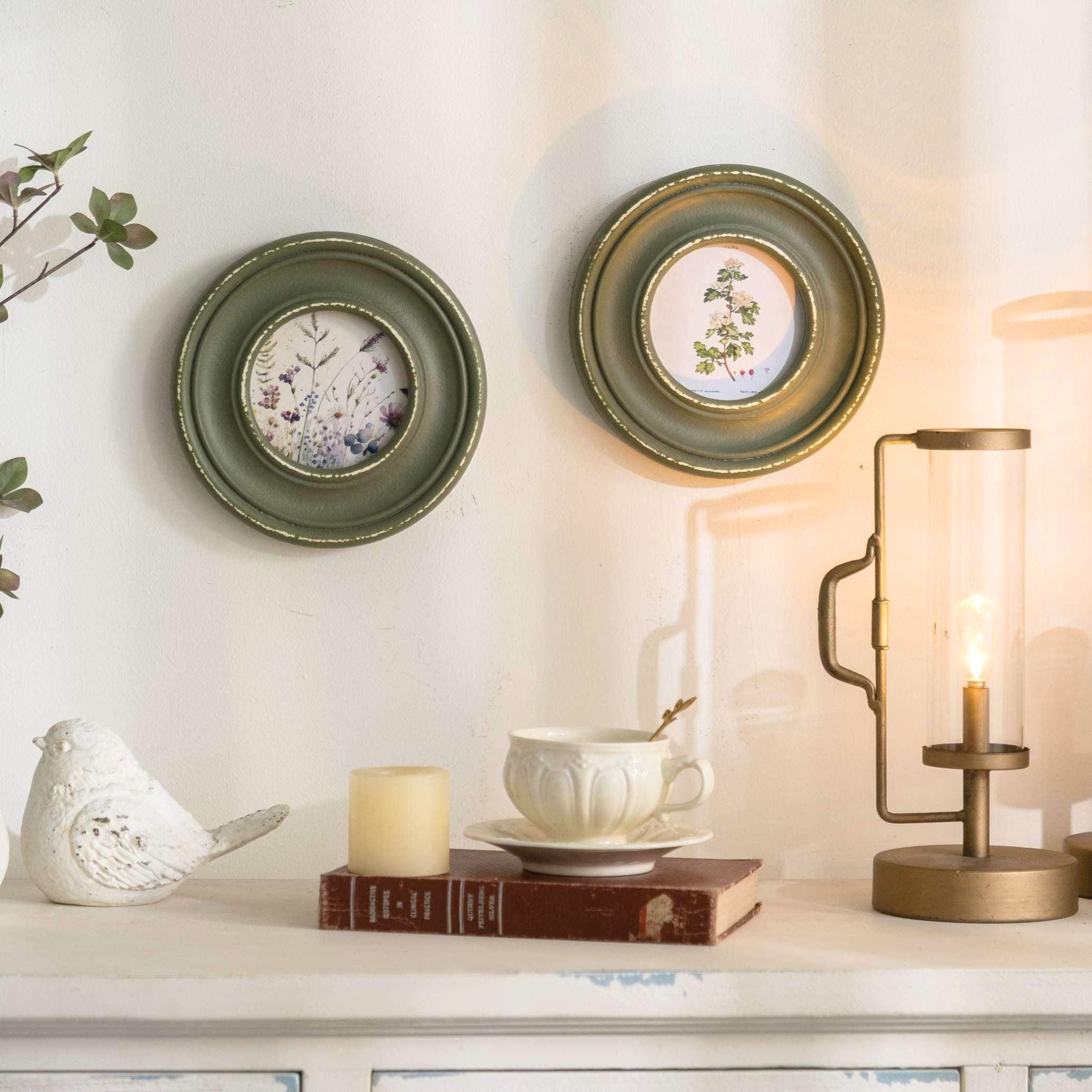 Pair of Hélène round botanical frames styled on a wall with candle and books.