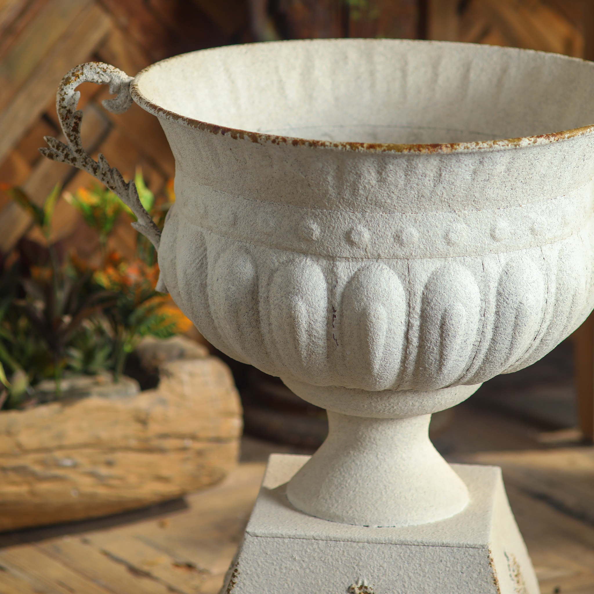 Side view of Héloïse iron urn planter showing handle profile and antique white finish
