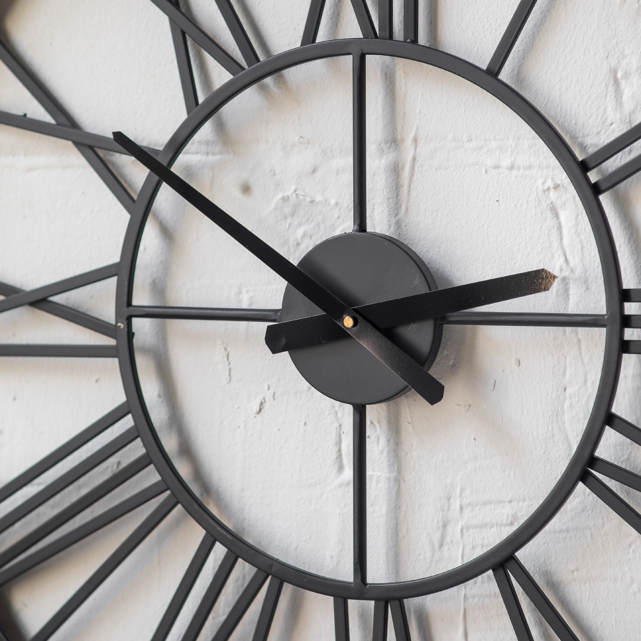 Close-up centre detail of Hugo wall clock showing the black iron clock hands, central hub, and inner ring construction