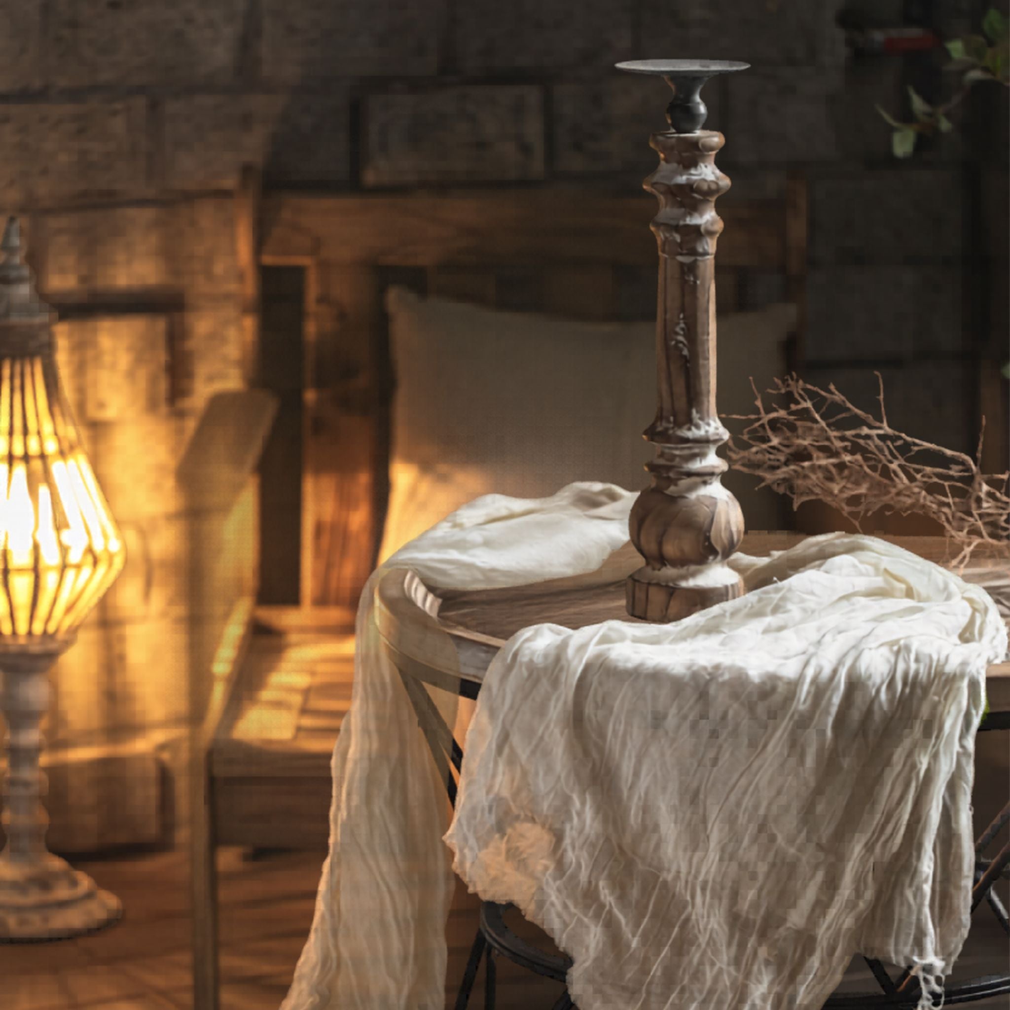 Jacques tall turned-timber pillar candle holder styled on a round table with cheesecloth and dried stems, full height. non lit