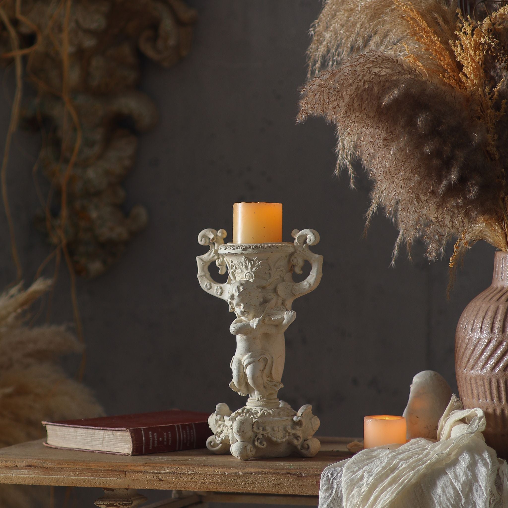 Jean Paul cherub candle holder lit with a pillar candle in a styled French Provincial setting
