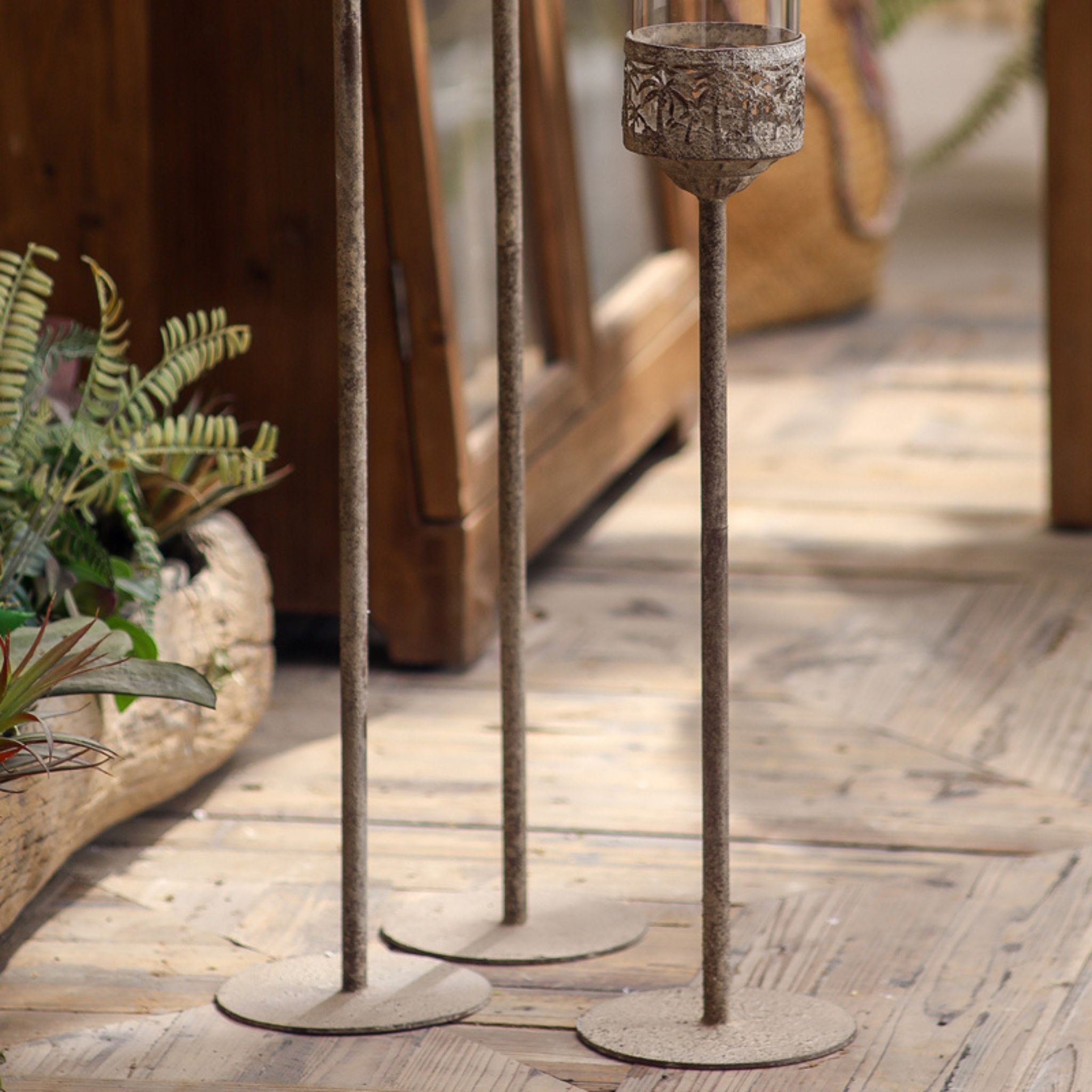Set of three candle holders on a timber floor showing full height and bases