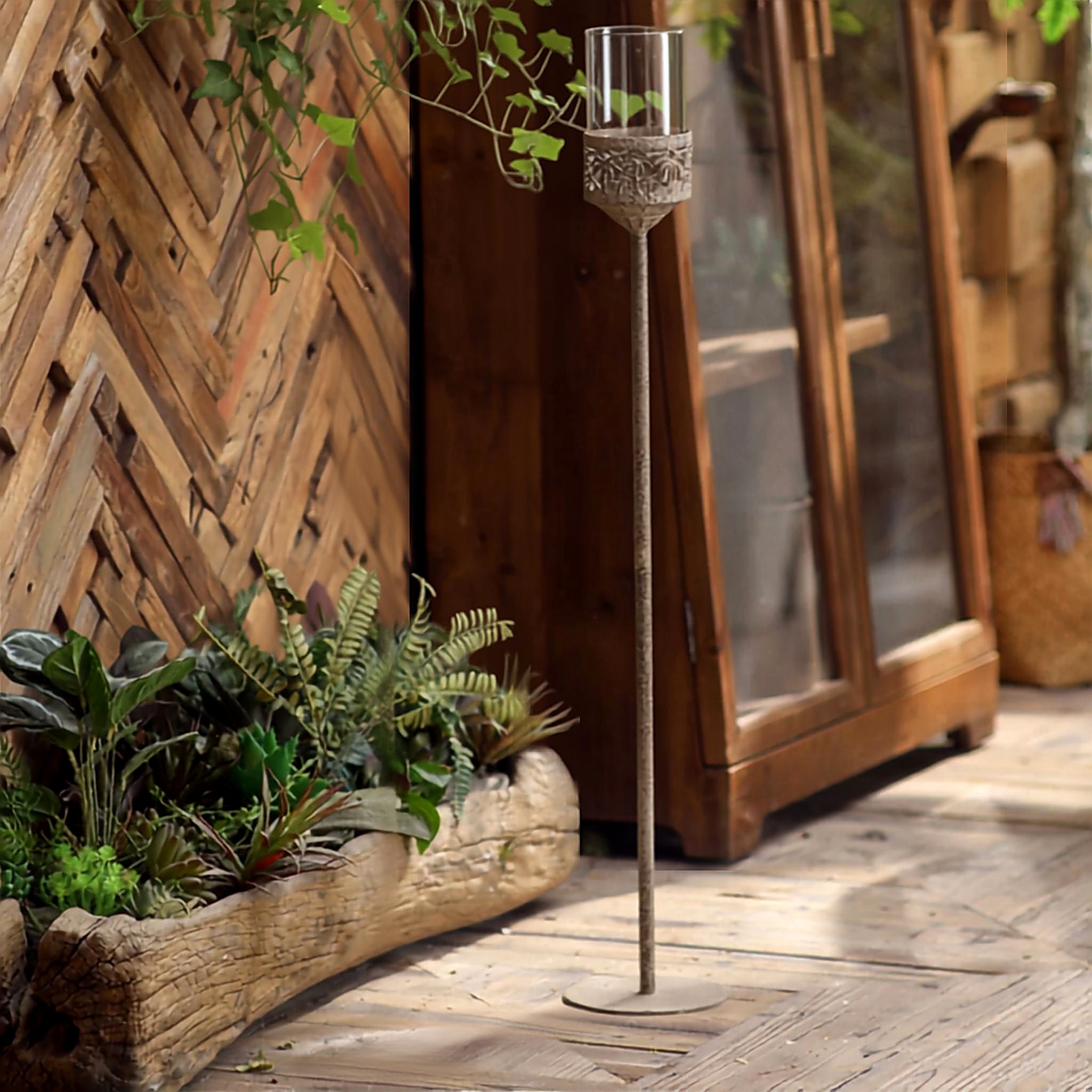 Jonathan French Provincial floor candle holder 87.5cm, aged metal stem with glass hurricane, on a timber table