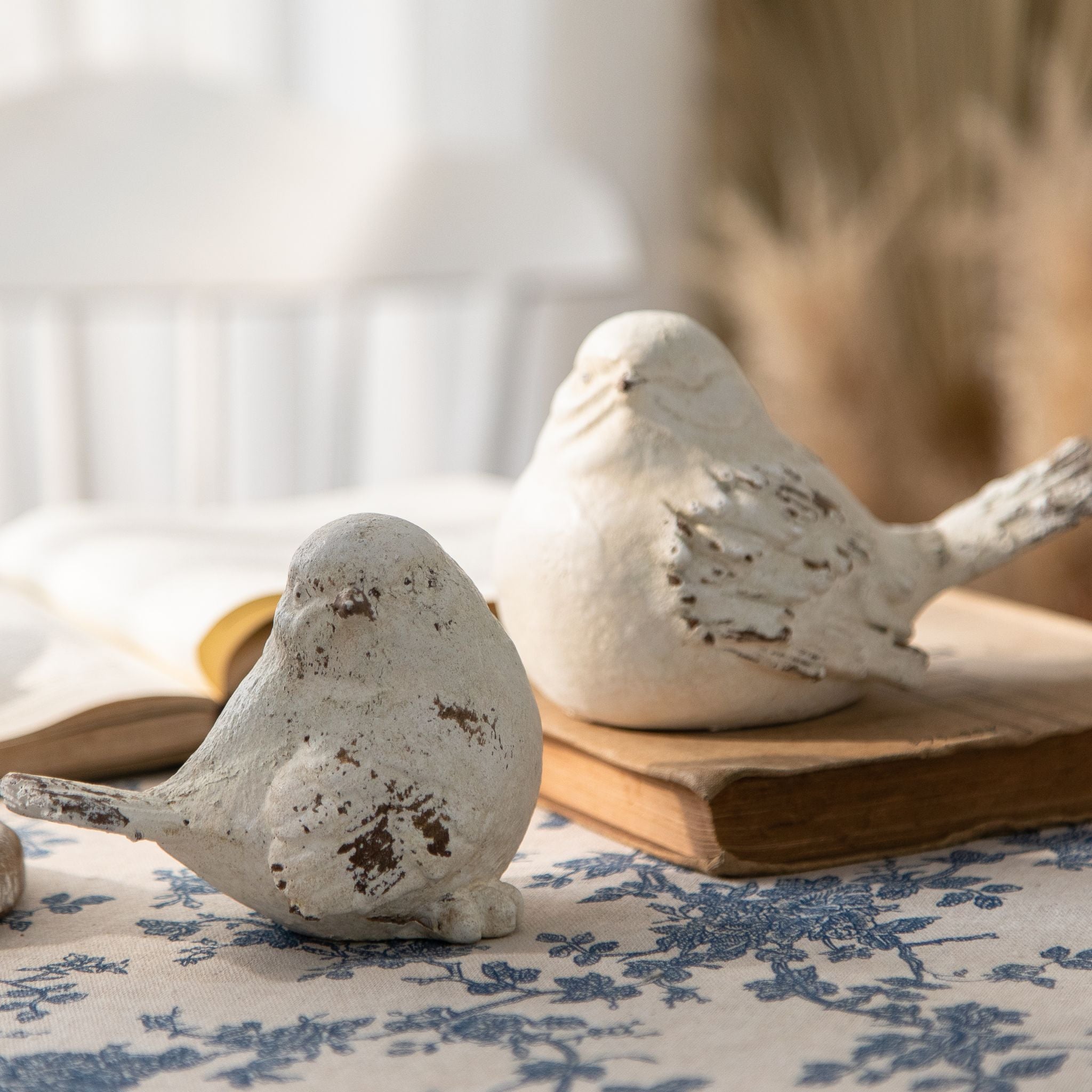 Bird figurines styled on stacked vintage books in soft light