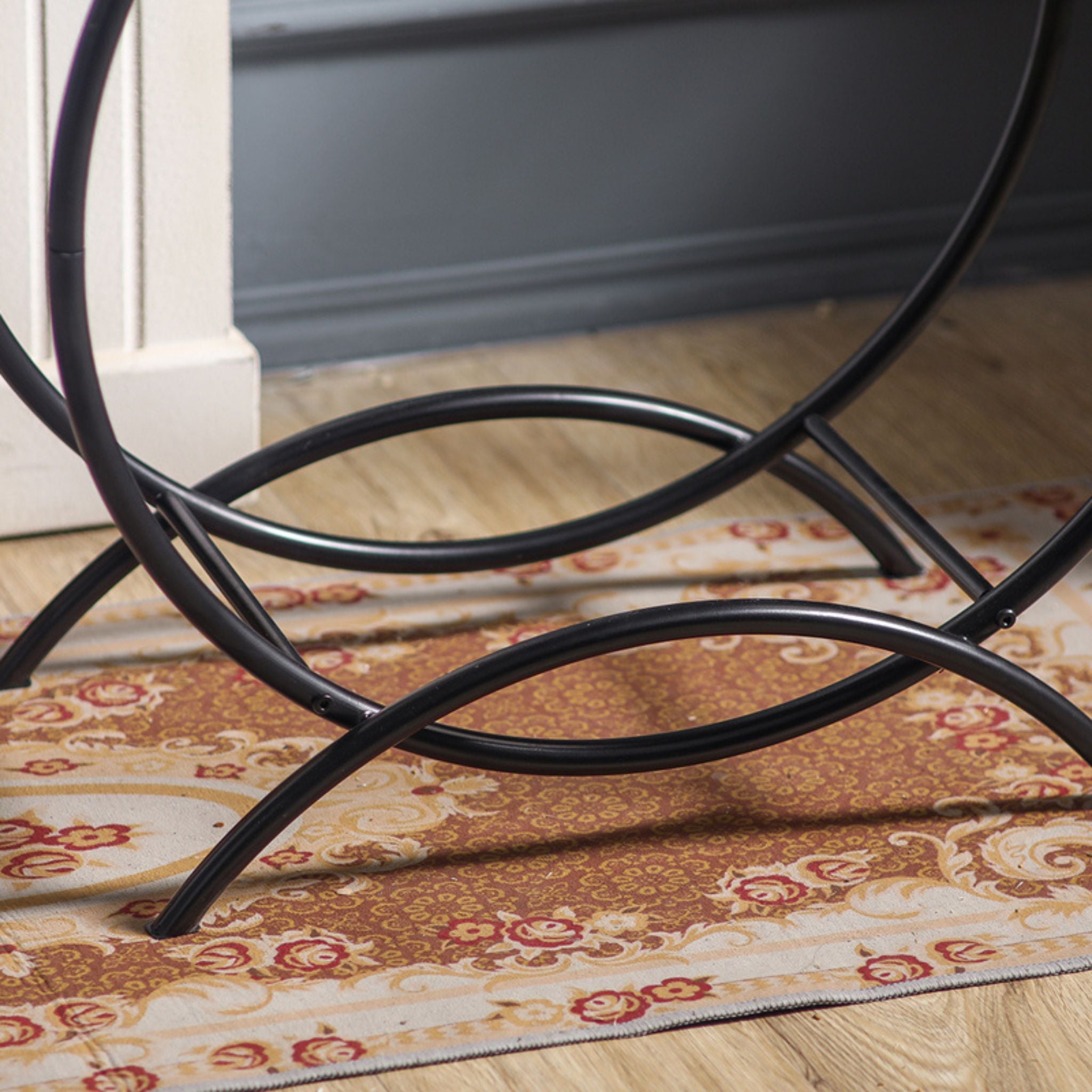 Close-up of the curved crossed feet and tubular steel frame at the base of the Emeric log hoop.