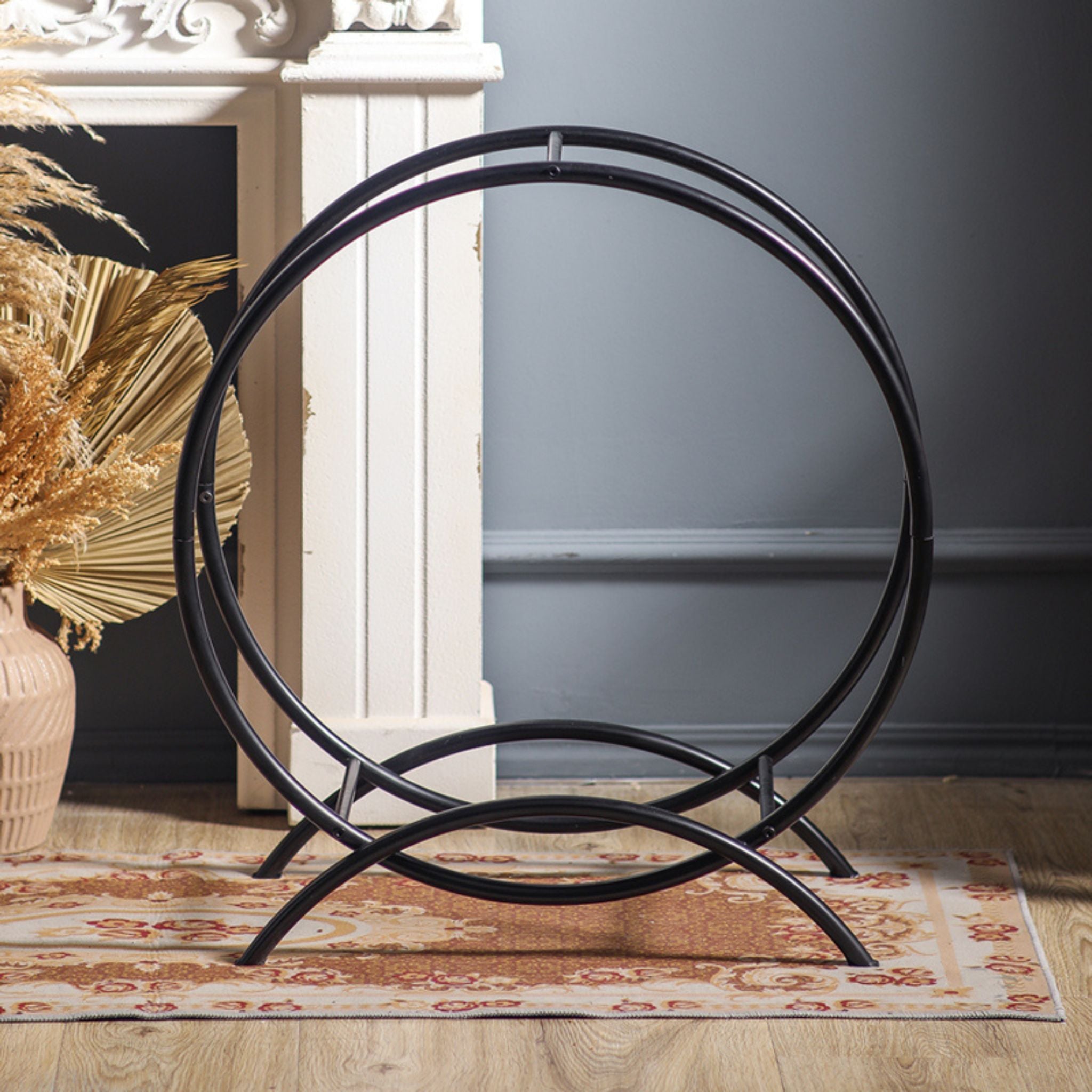 The Emeric round log hoop shown empty from the front, a matte black steel circle on curved feet.