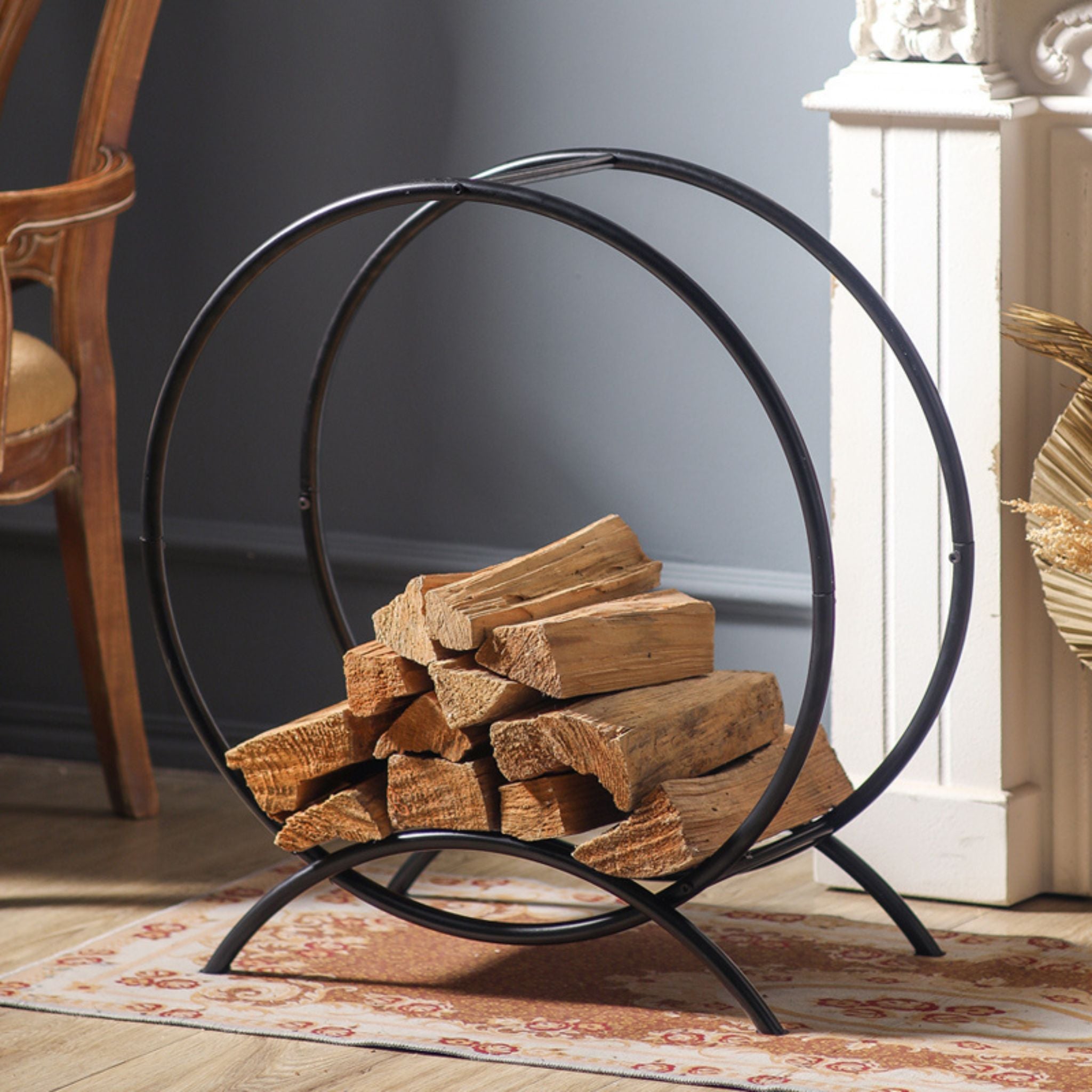 Angled view of the Emeric round log rack loaded with firewood in a French country room.