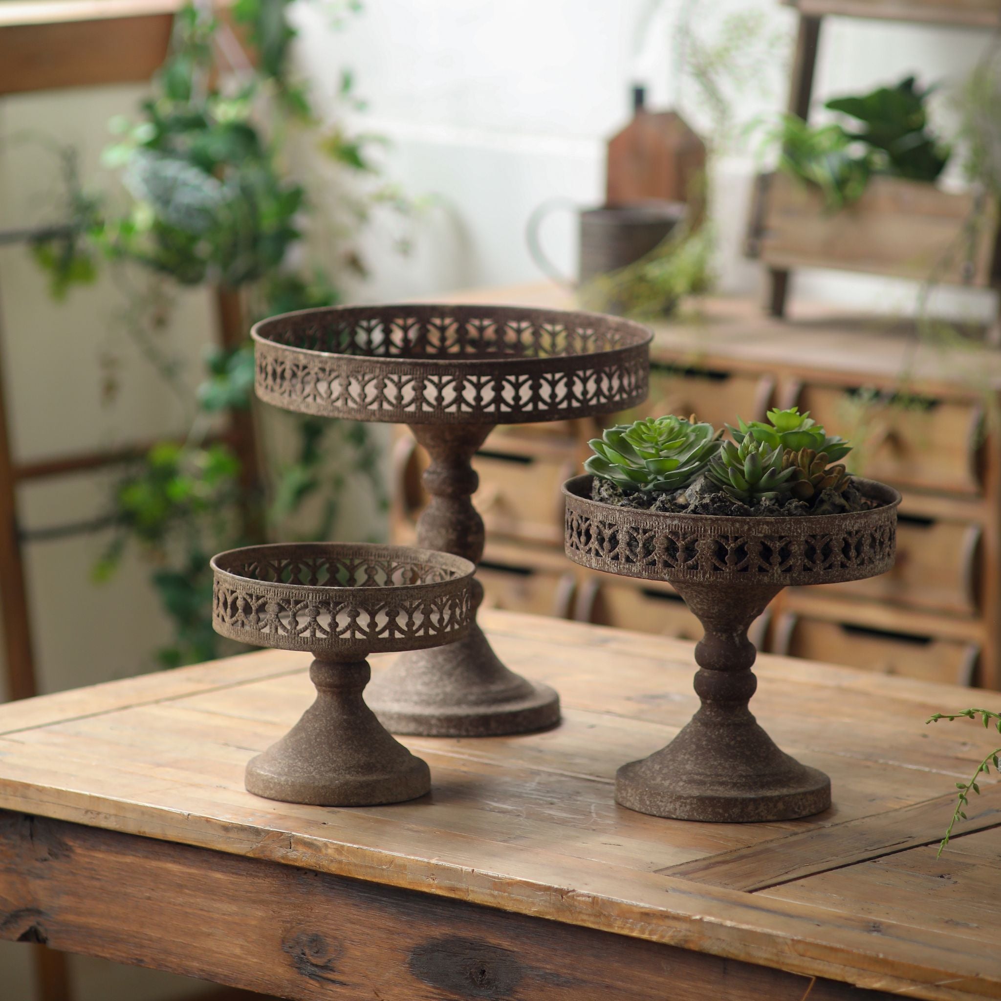 Three pedestal stands in graduated sizes shown together on a timber table.