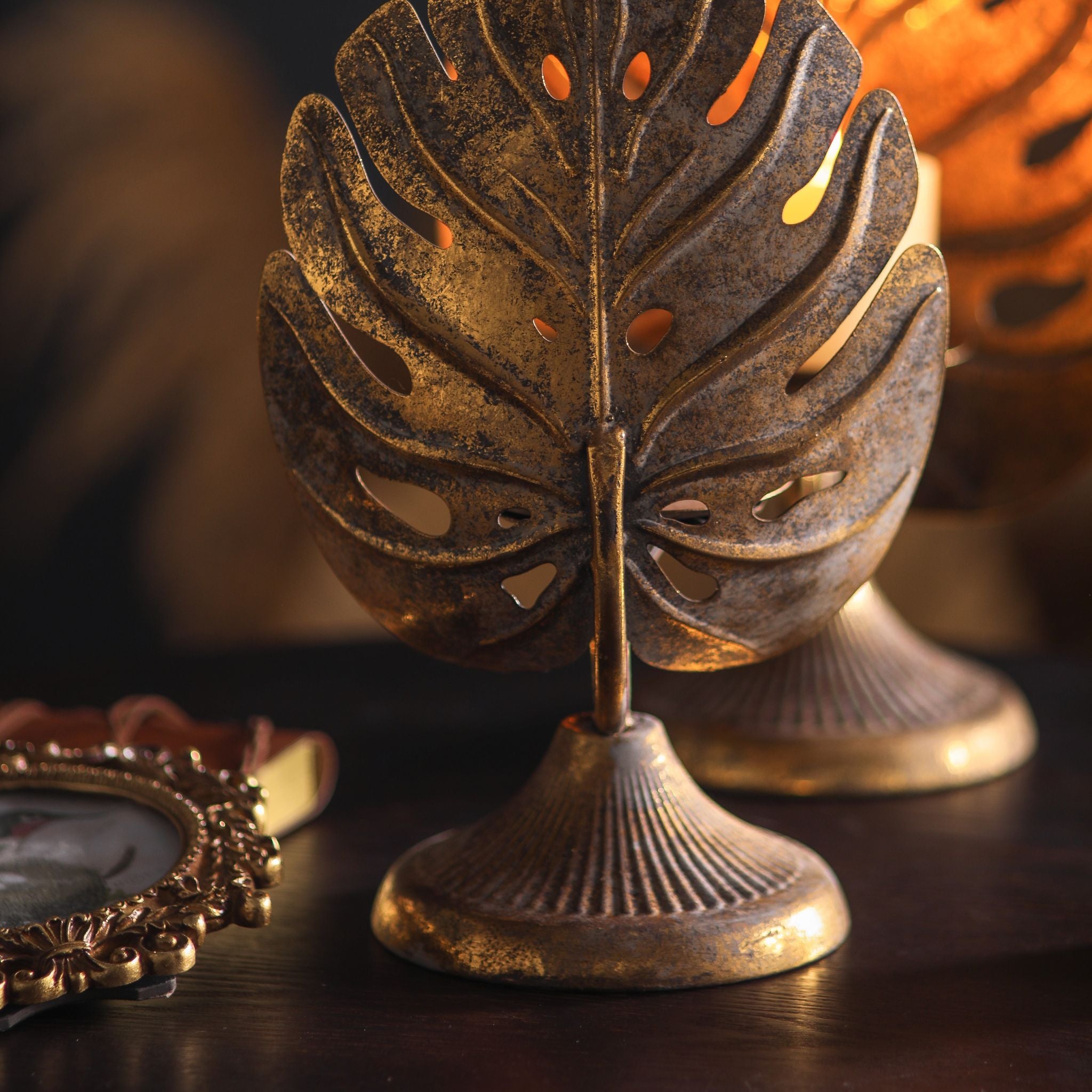 Rear view of the pierced monstera leaf and fluted pedestal base in aged metal with antique gold.