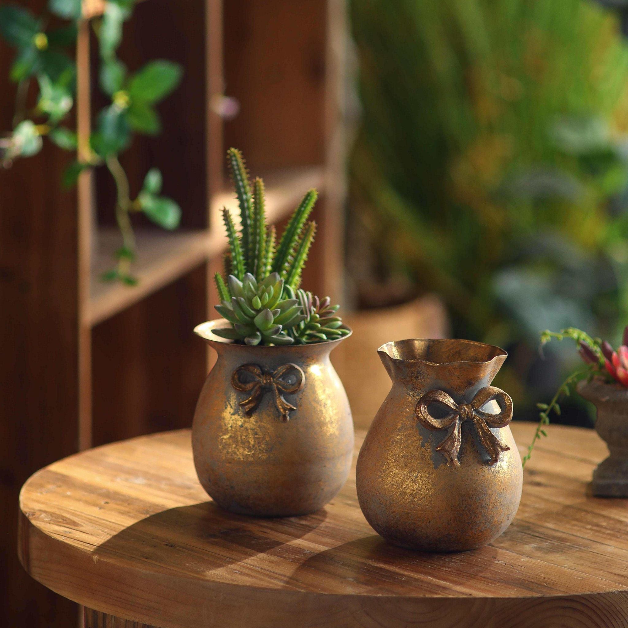 Noel set of two antique-gold bow vases, a flared pot planted with succulents and a ruffled pot. Hero.