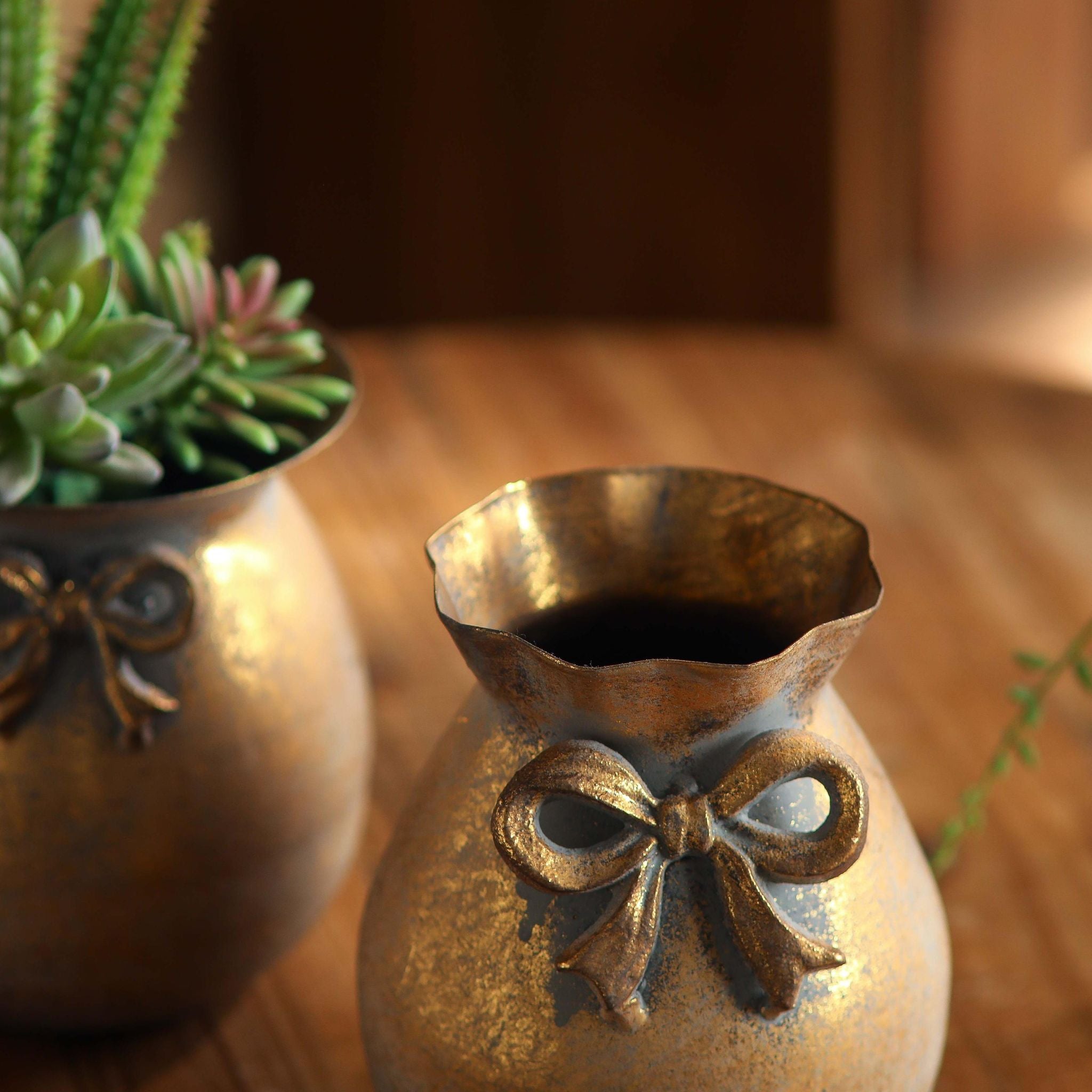 Noel bow vase, close detail of the cast bow and worn antique-gold finish.