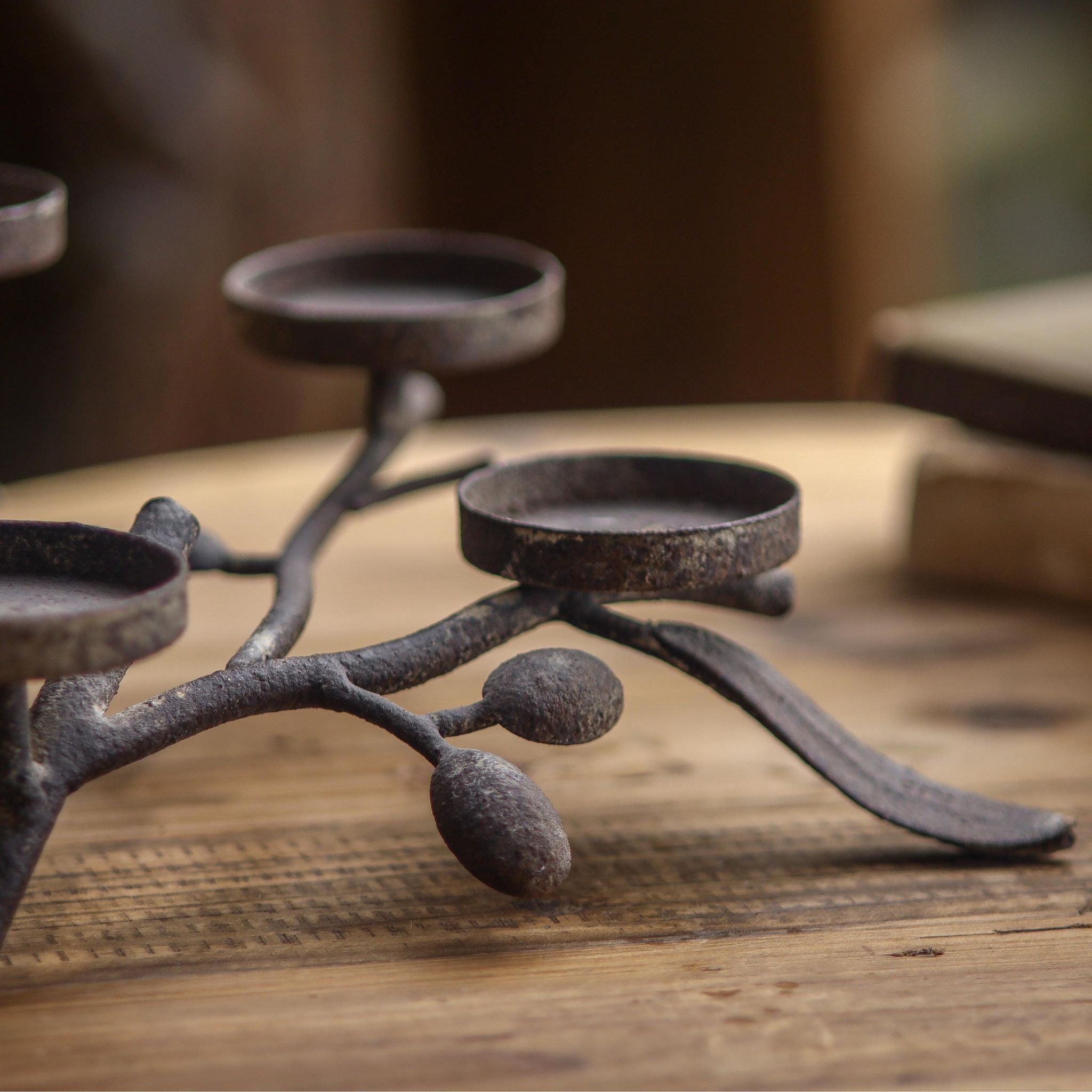 Close view of the three staggered candle plates and olive leaves in worn aged metal.