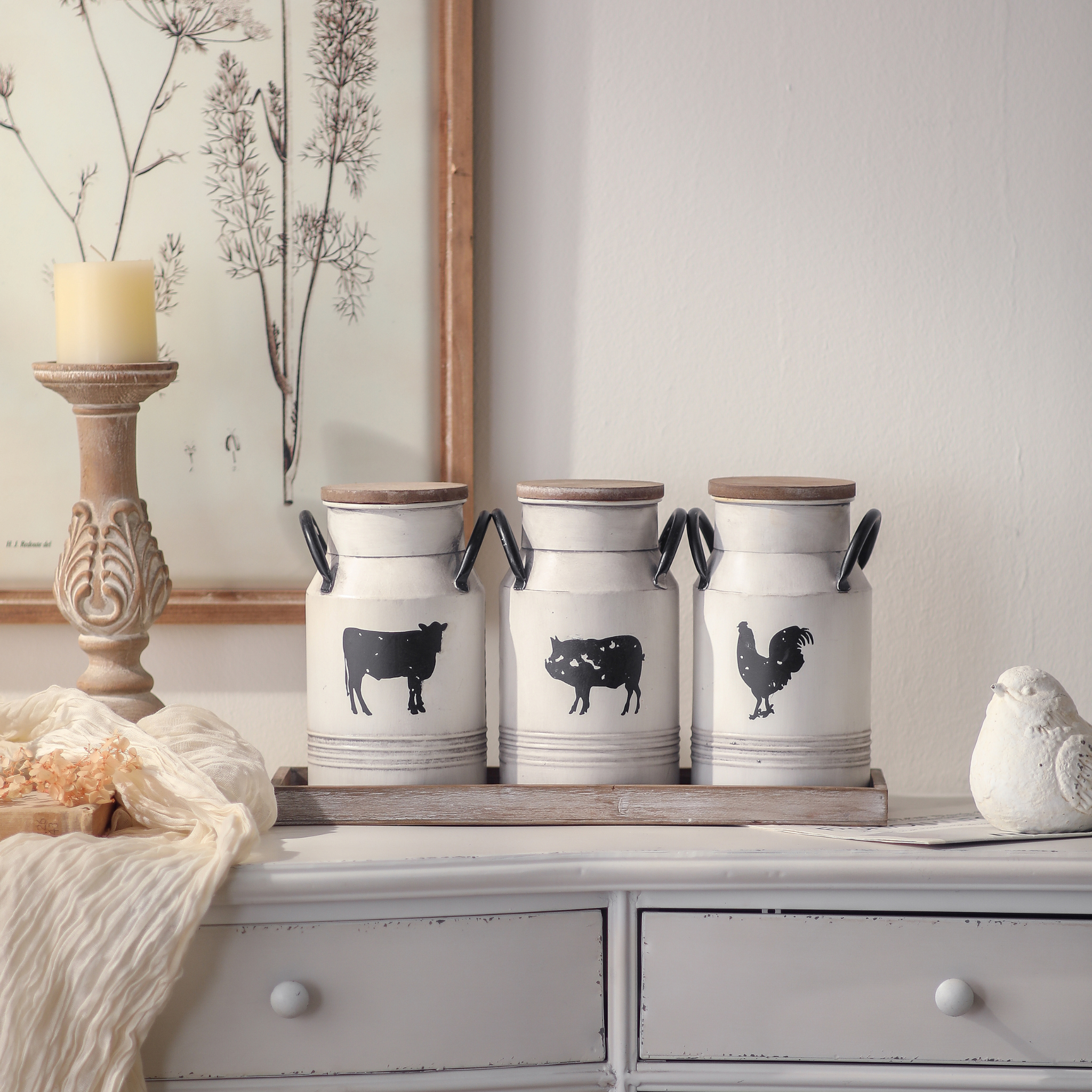 The Petite Ferme Set of three farmhouse milk can canisters on tray styled on a French Provincial dresser with botanical art and candlestick