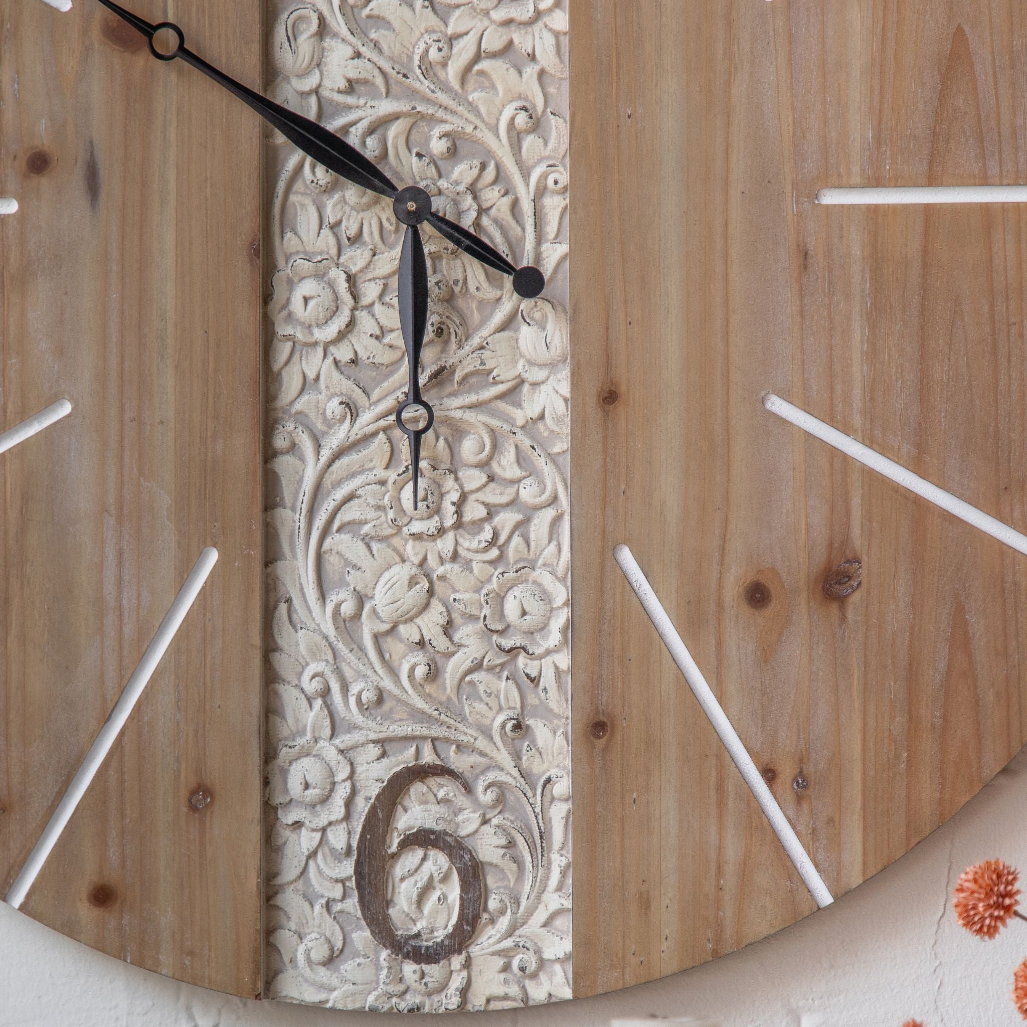 Close-up of Pierre's central carved floral panel showing the whitewashed scrollwork detail, the carved 6 numeral, and black iron clock hands