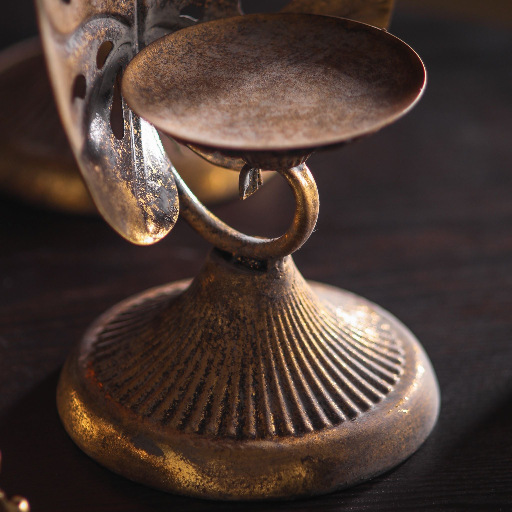 Close-up of the candle dish, scroll connector, and fluted base, mottled antique gold finish.