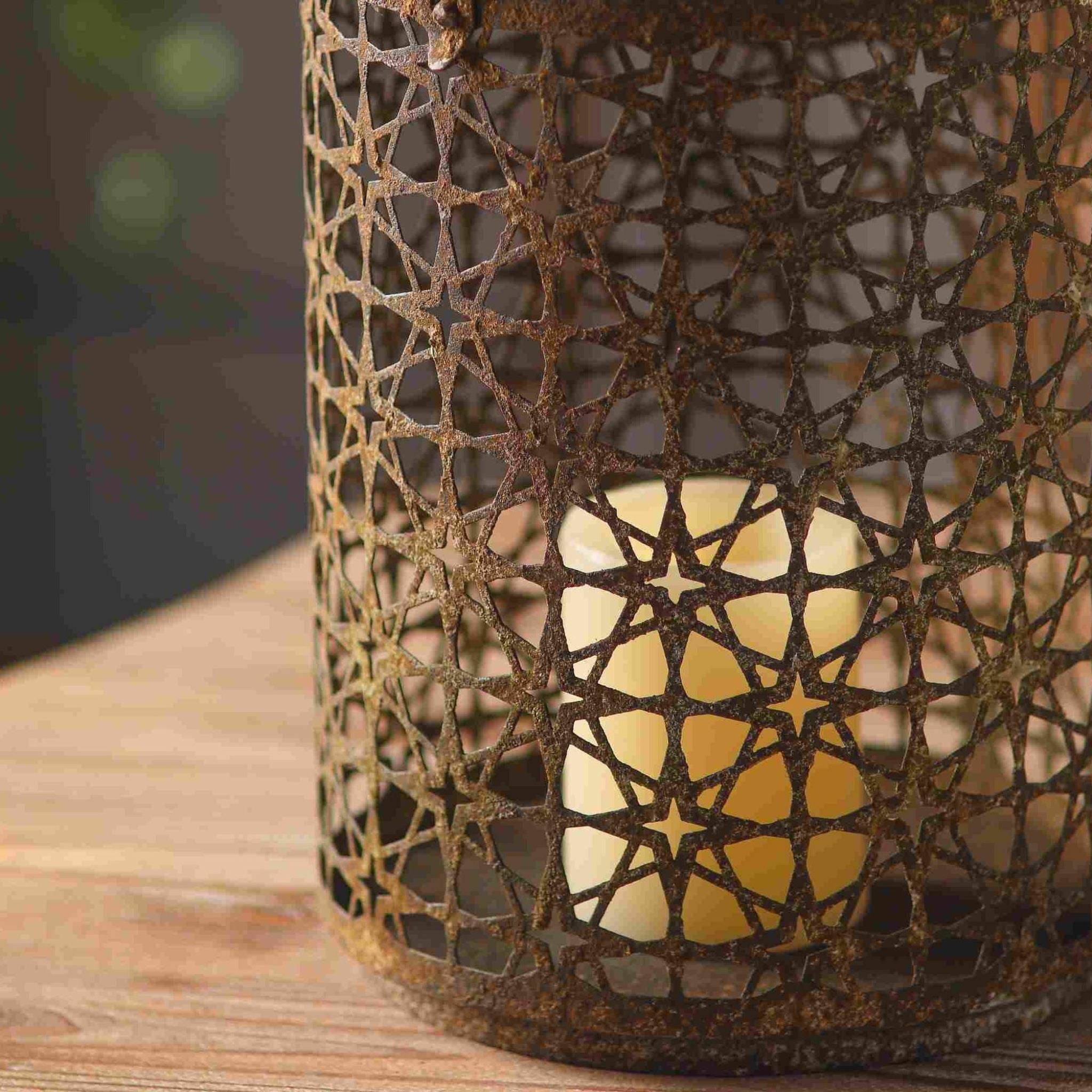 Close detail of the Rueben lantern star-pierced metalwork with warm candlelight glowing through the geometric pattern.