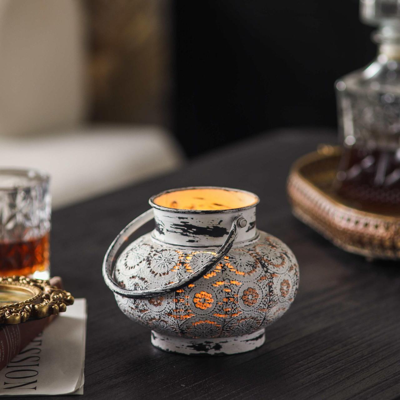 Close angle of Soraya lantern lit, pinpoint candlelight scattering through embossed floral medallions