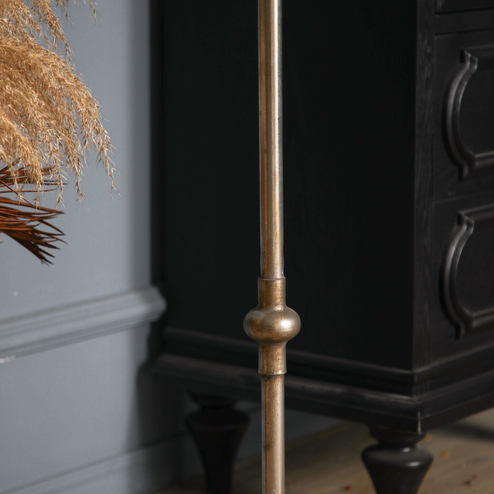 Close detail of the Sylvestre candle holder's slender stem and turned ball knop in antique gold.