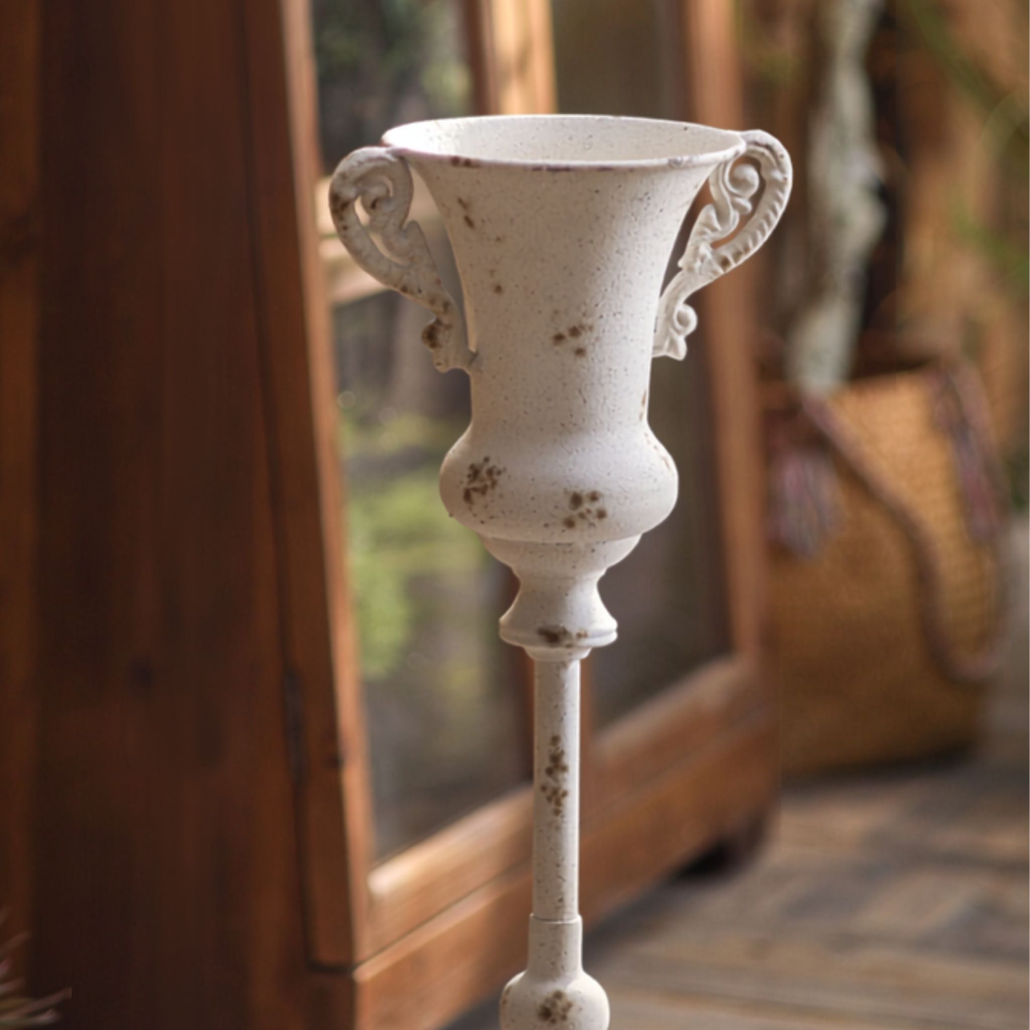 Thierry close-up of the urn cup with scrolled handles, chipped antique white with rust spotting.