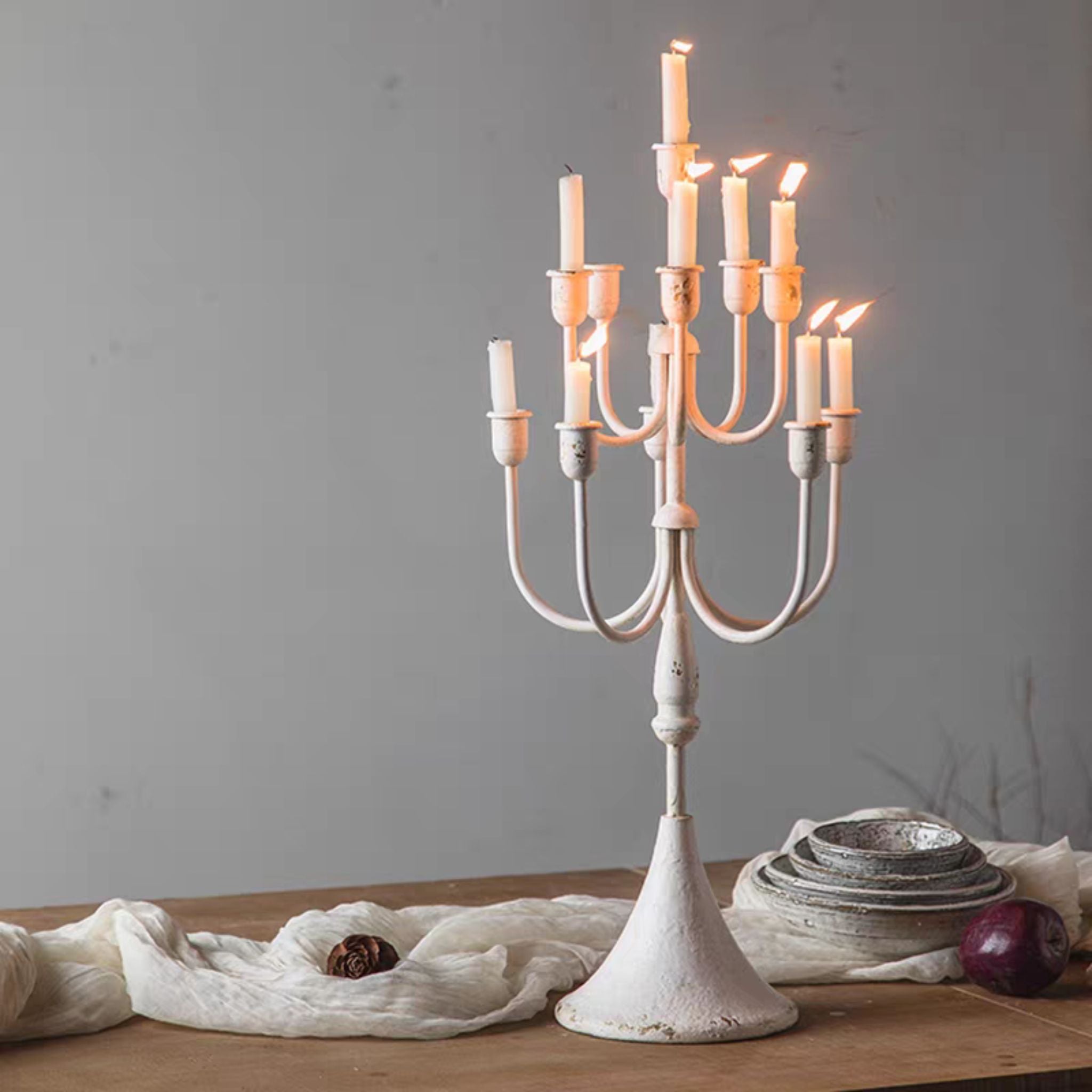 Tiered candelabra lit on a dining table in distressed cream.