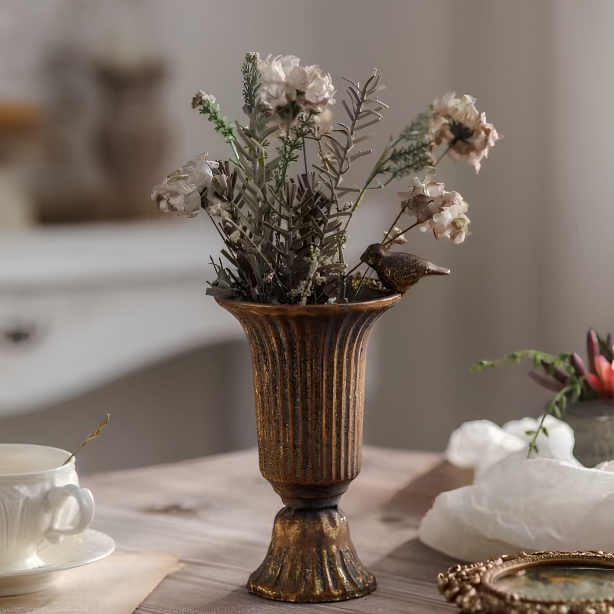 Valentine antique gold urn vase holding dried flowers, styled indoors with a teacup and gold frame.