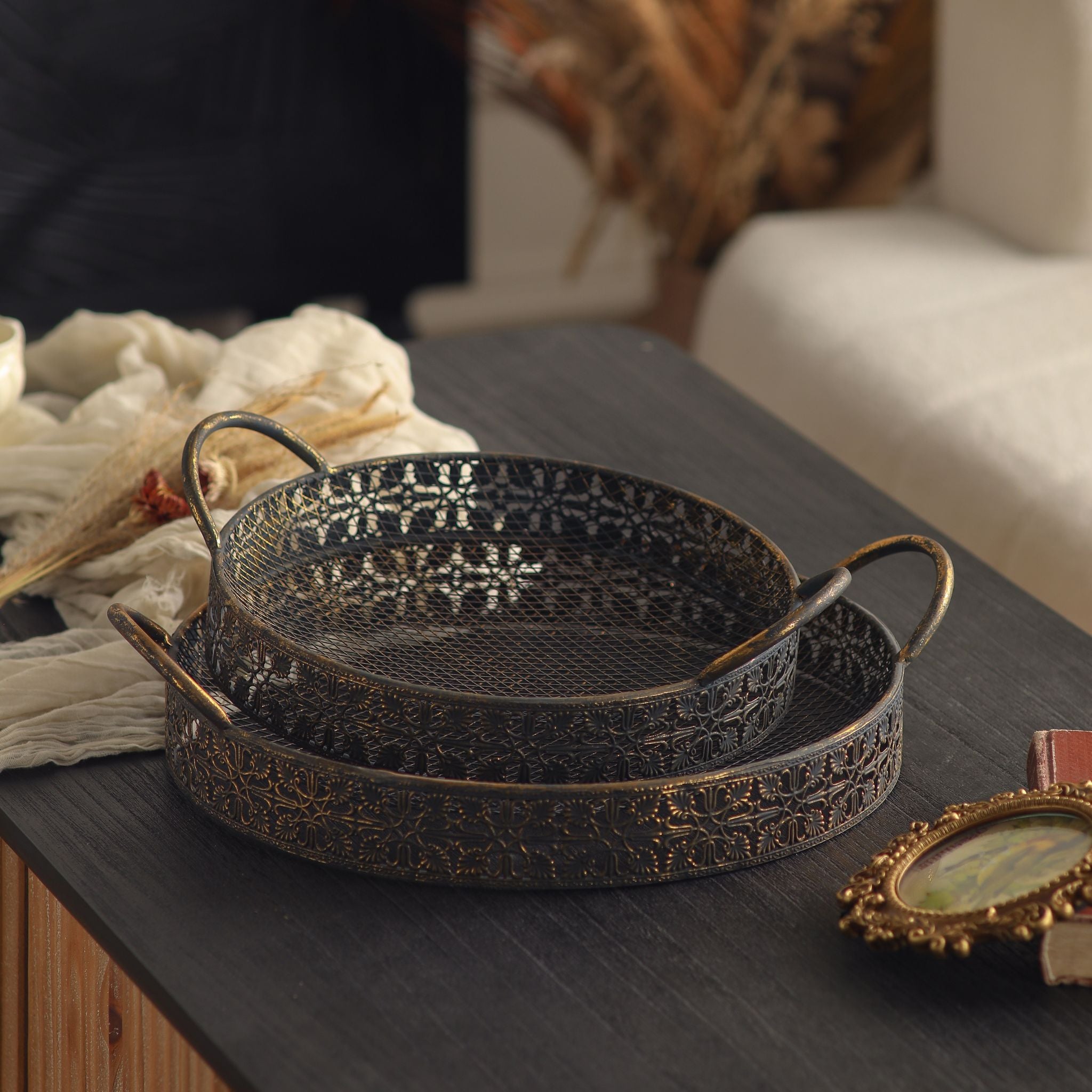 Valerie set of 2 round metal trays in antique gold over dark metal, the smaller nested in the larger, with mesh bases, filigree sides, and looped handles.