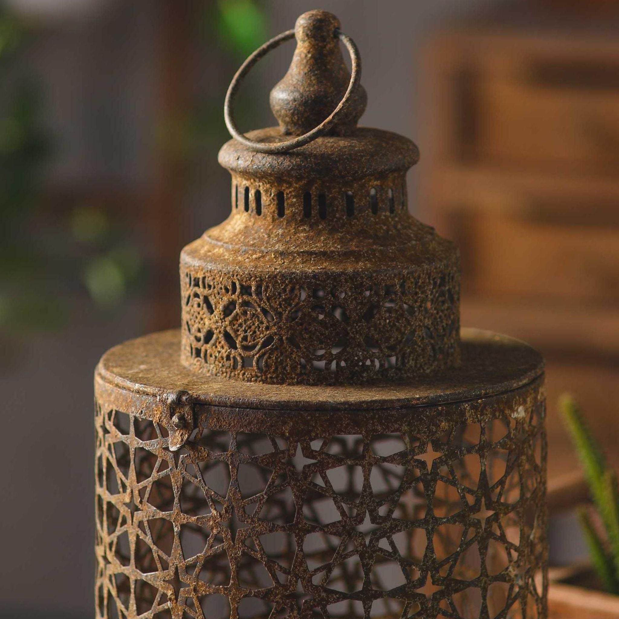 Close detail of the Yannick lantern domed cap, pierced aged metal with a weathered rust finish, ring handle and finial.