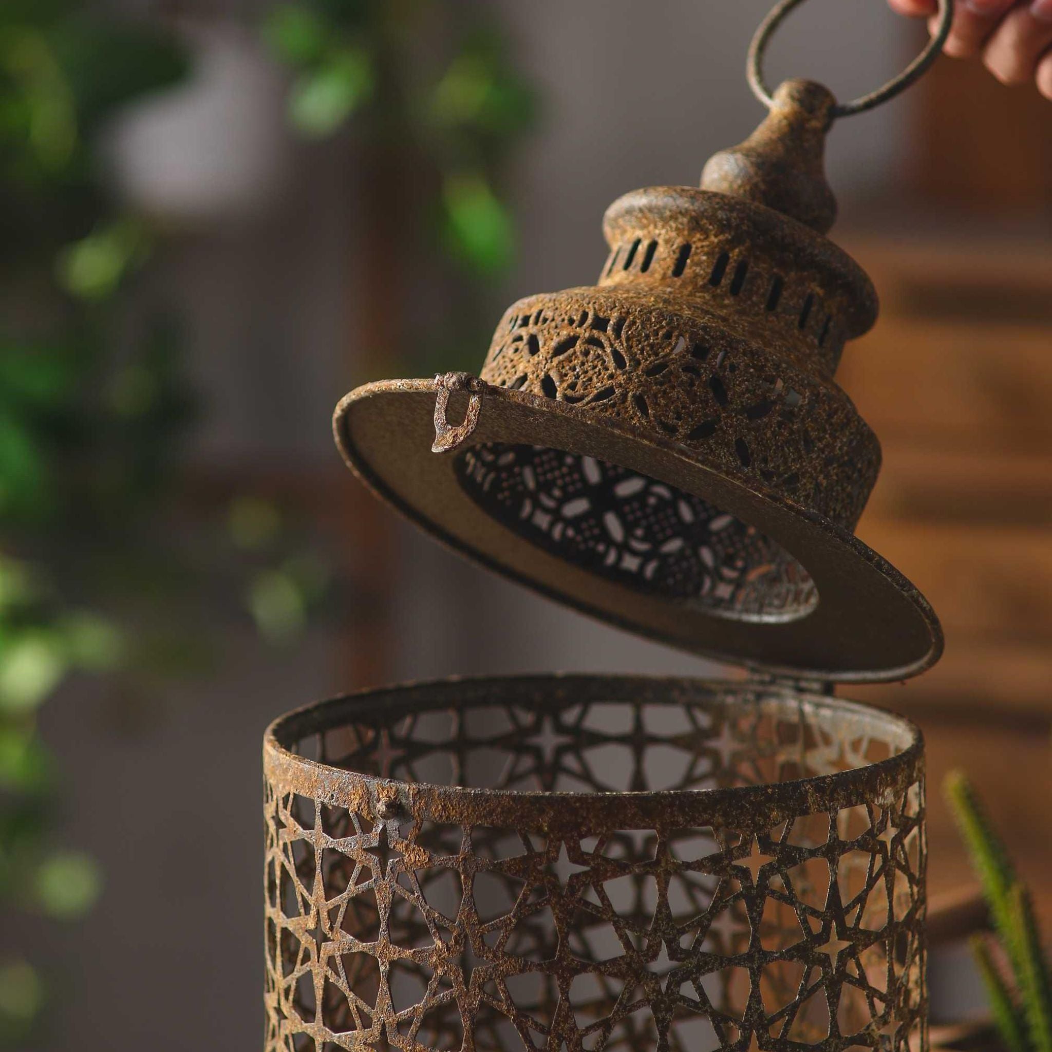 Yannick lantern with its hinged domed cap lifted open, showing the pierced metal lid and how a candle sits inside.