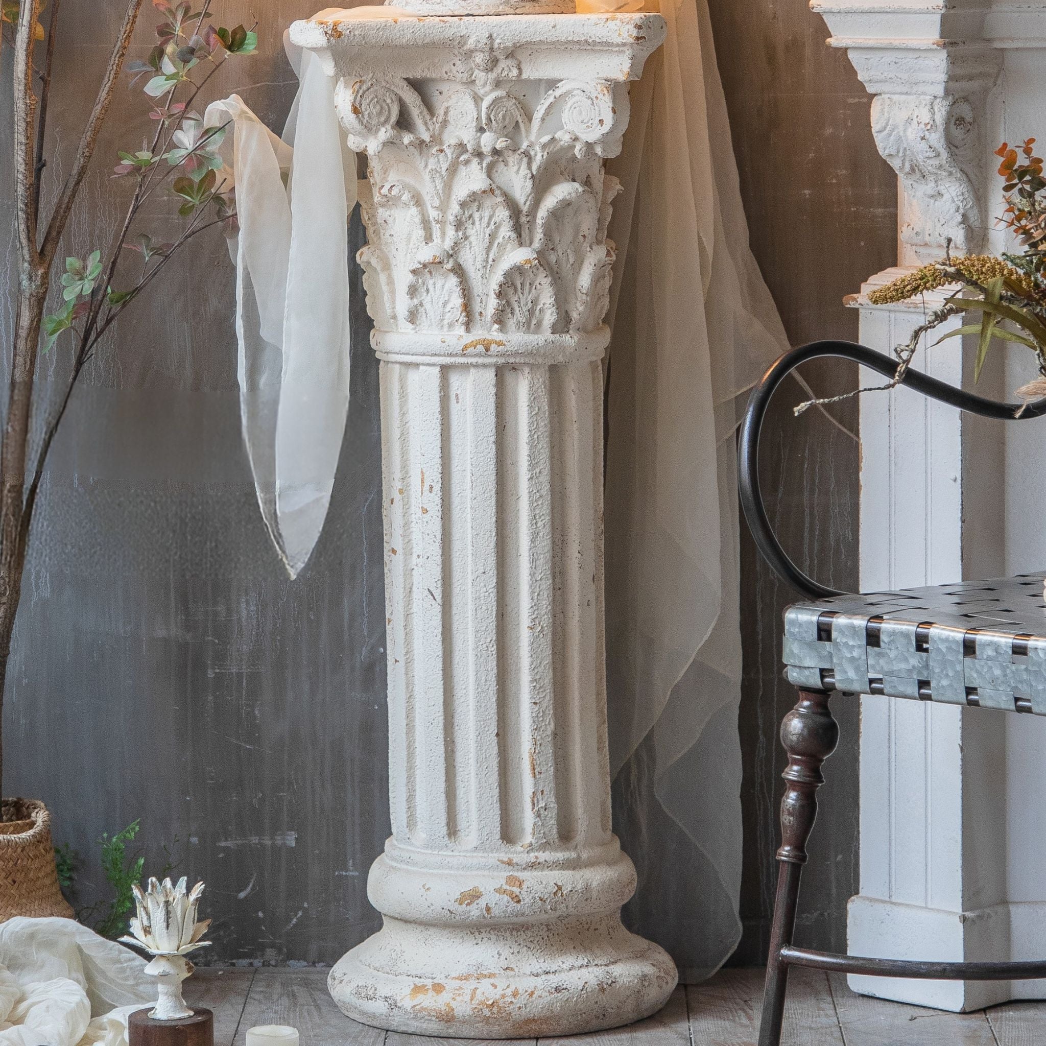Yvonne column pedestal styled in a château-style room with a sheer drape and a finial on top.