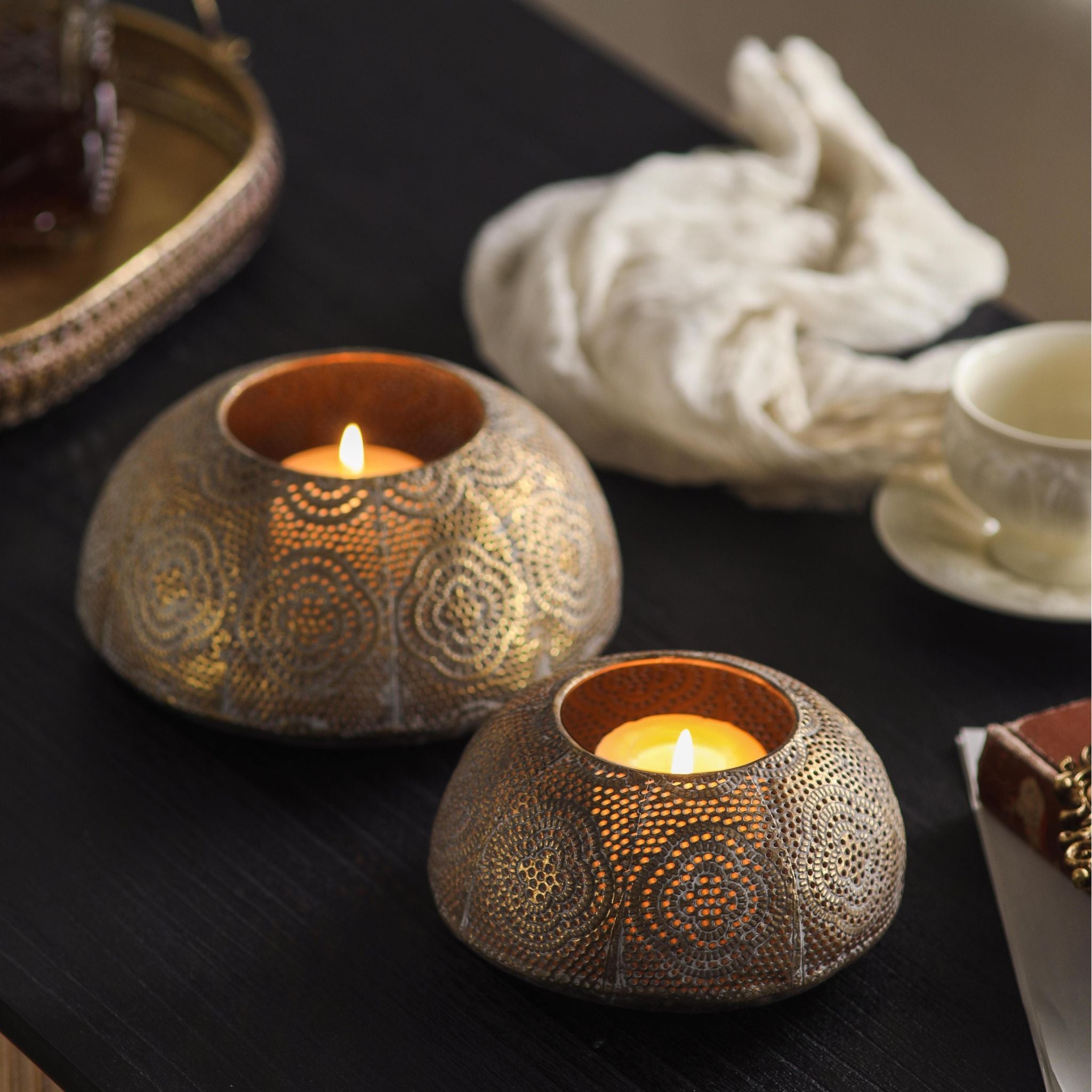 Pair of pierced metal tealight holders lit in a warm styled scene
