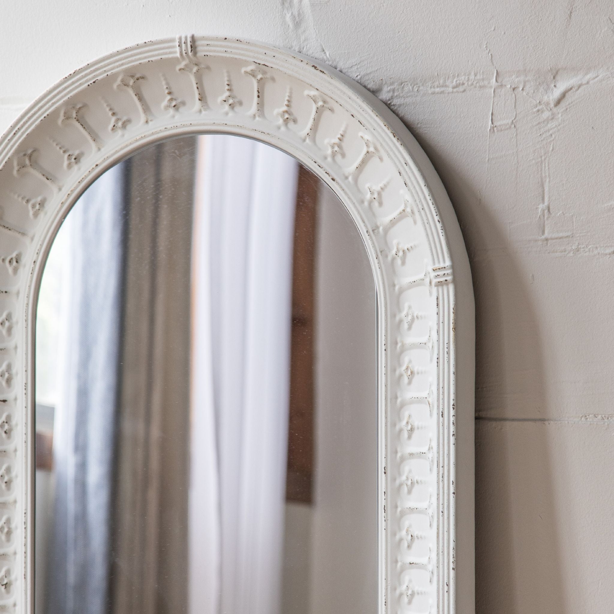 Theron white arched mirror beside a floral table in a bright room