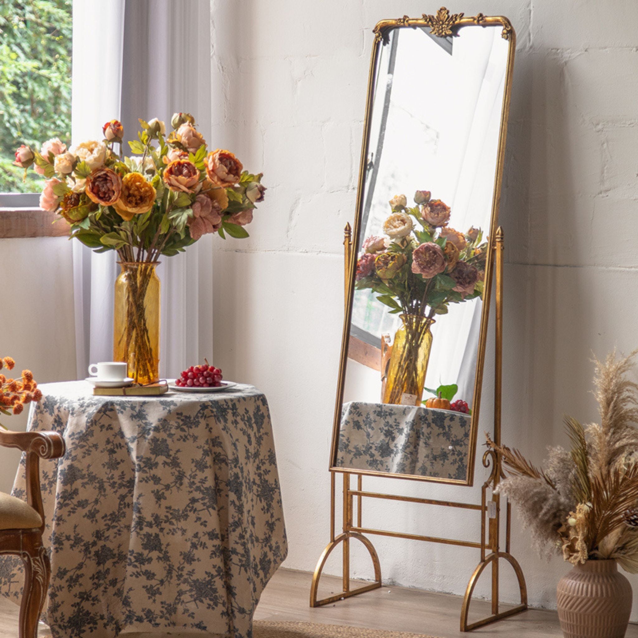 Sorrento full length cheval mirror in antique gold with floral crest standing in a room