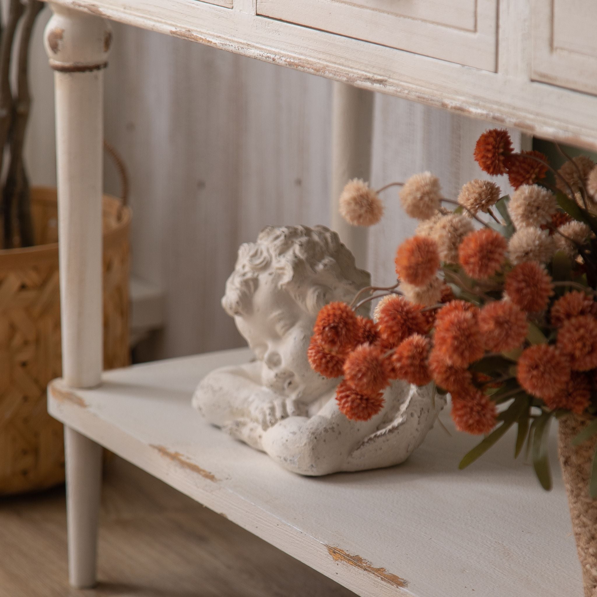 Seville console lower shelf styled with a sleeping cherub and basket of flowers
