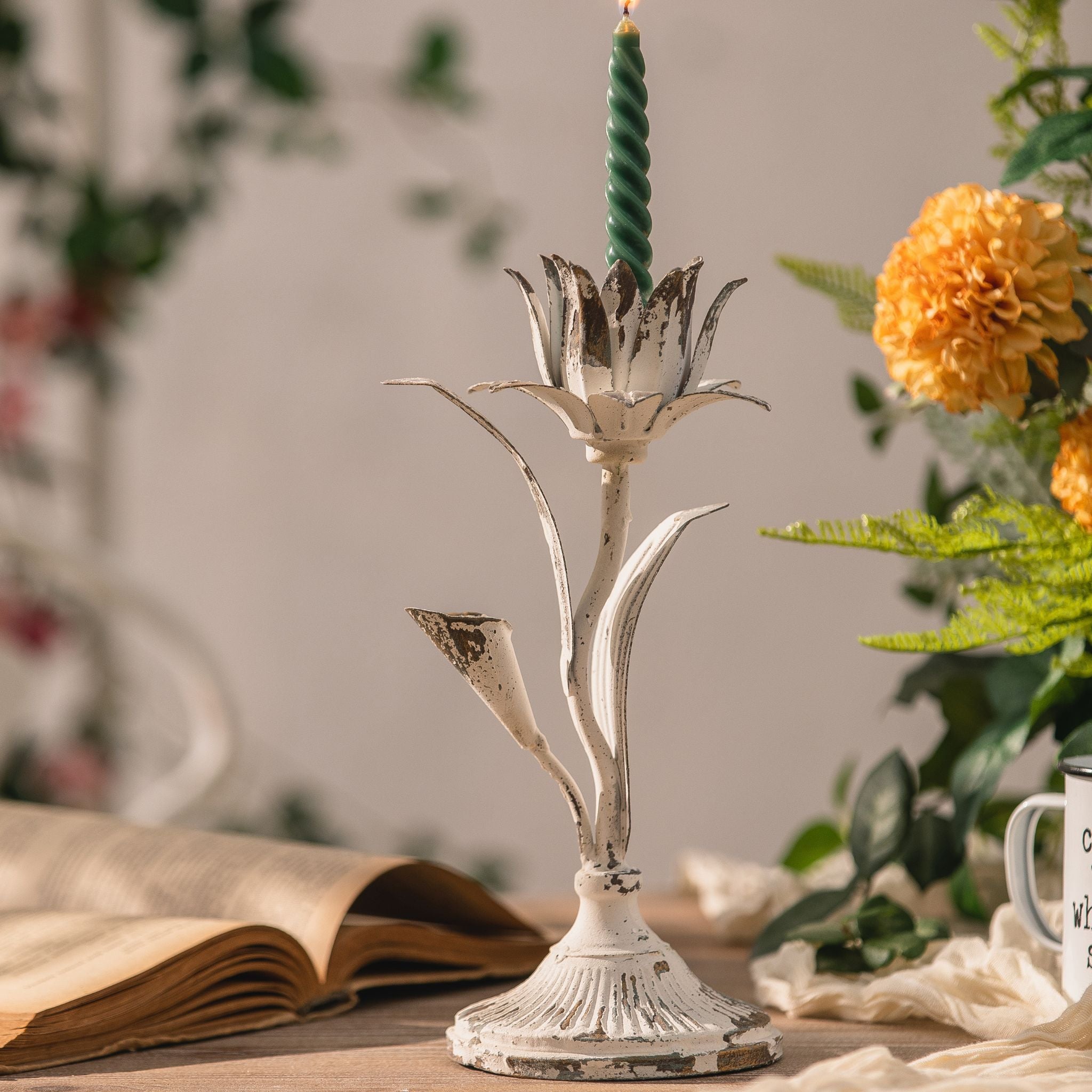 Silvio iron flower candlestick with lit candle styled beside marigolds and an open book