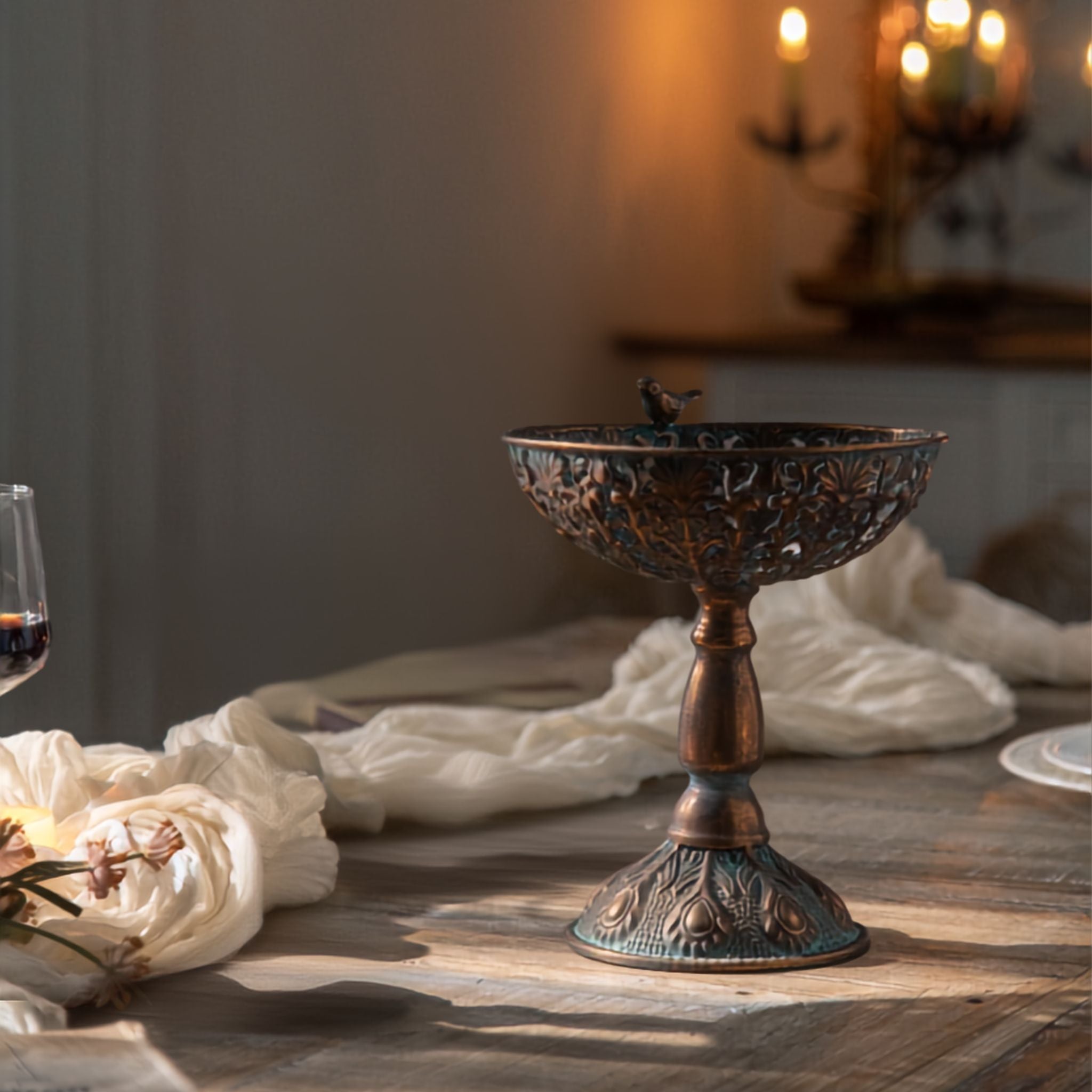 Sandro pedestal bowl in a bronze style finish with verdigris patina and a bird perched on the rim