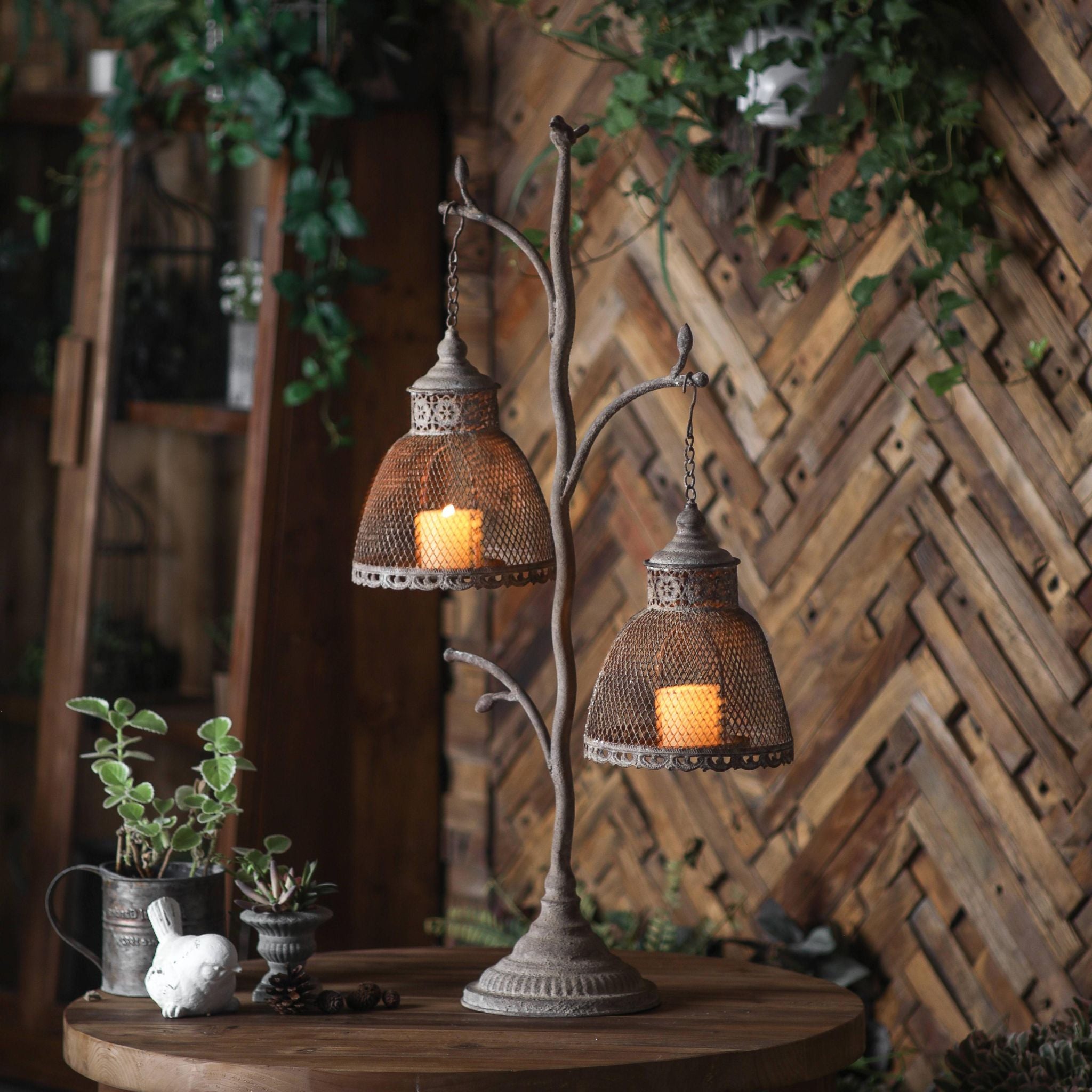 Giorgio hanging lantern stand in aged iron with two mesh shades on a garden table