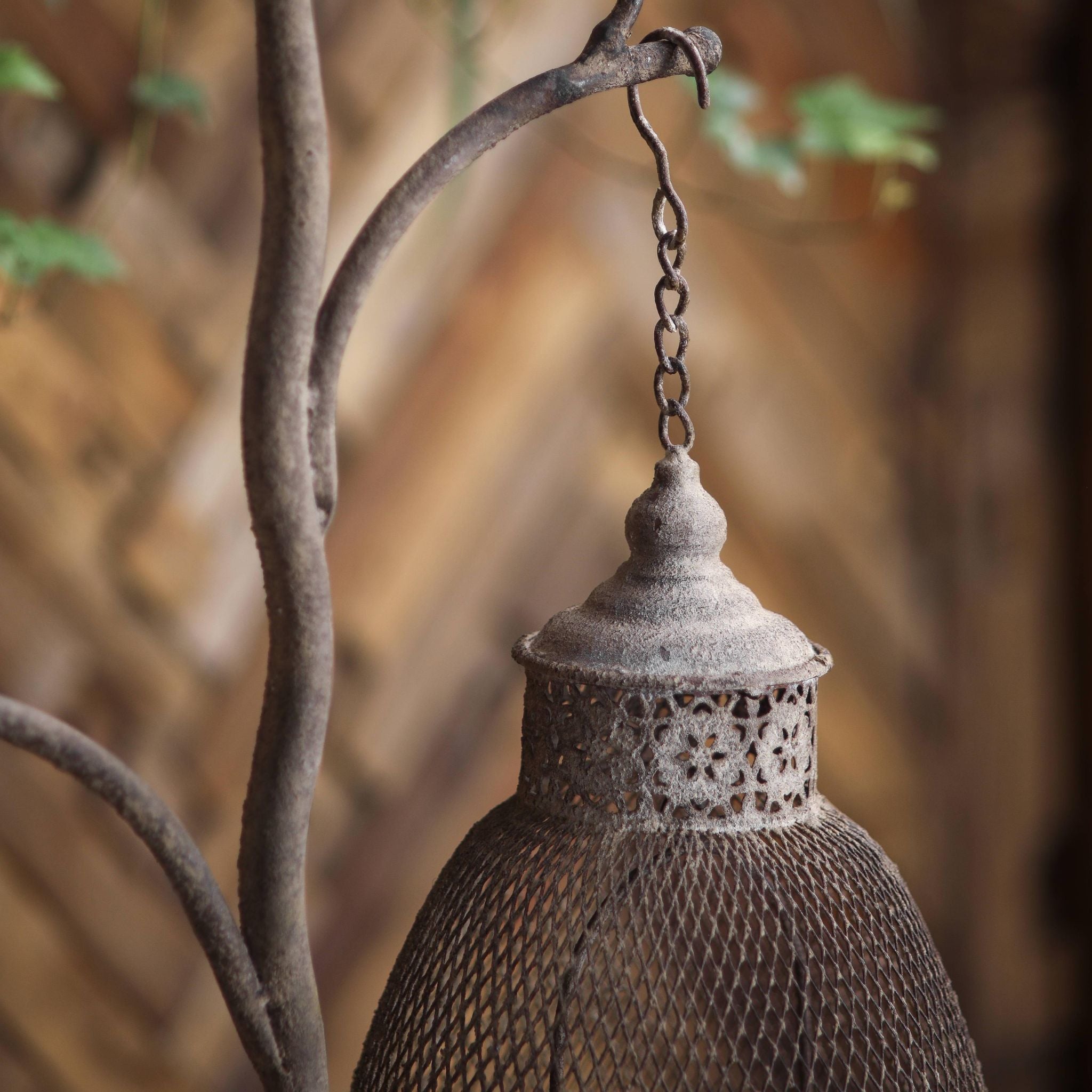 Giorgio branch lantern stand with candles glowing through the mesh shades at dusk
