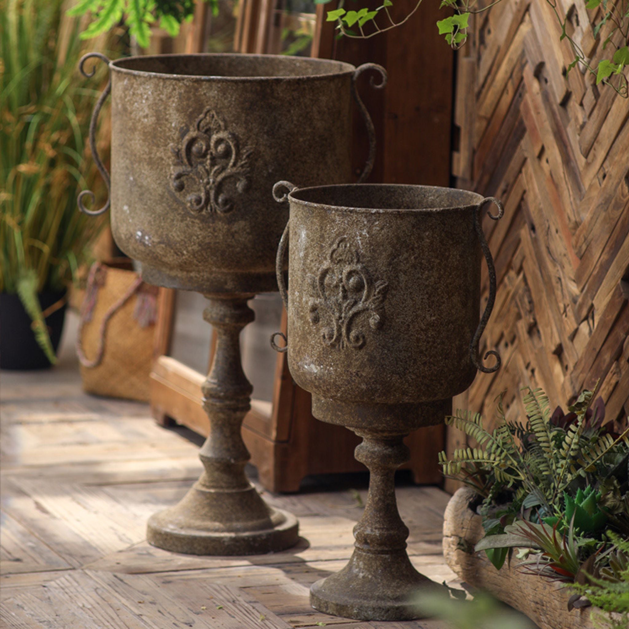 Ronda pedestal urn planter styled on a timber deck against a herringbone wall