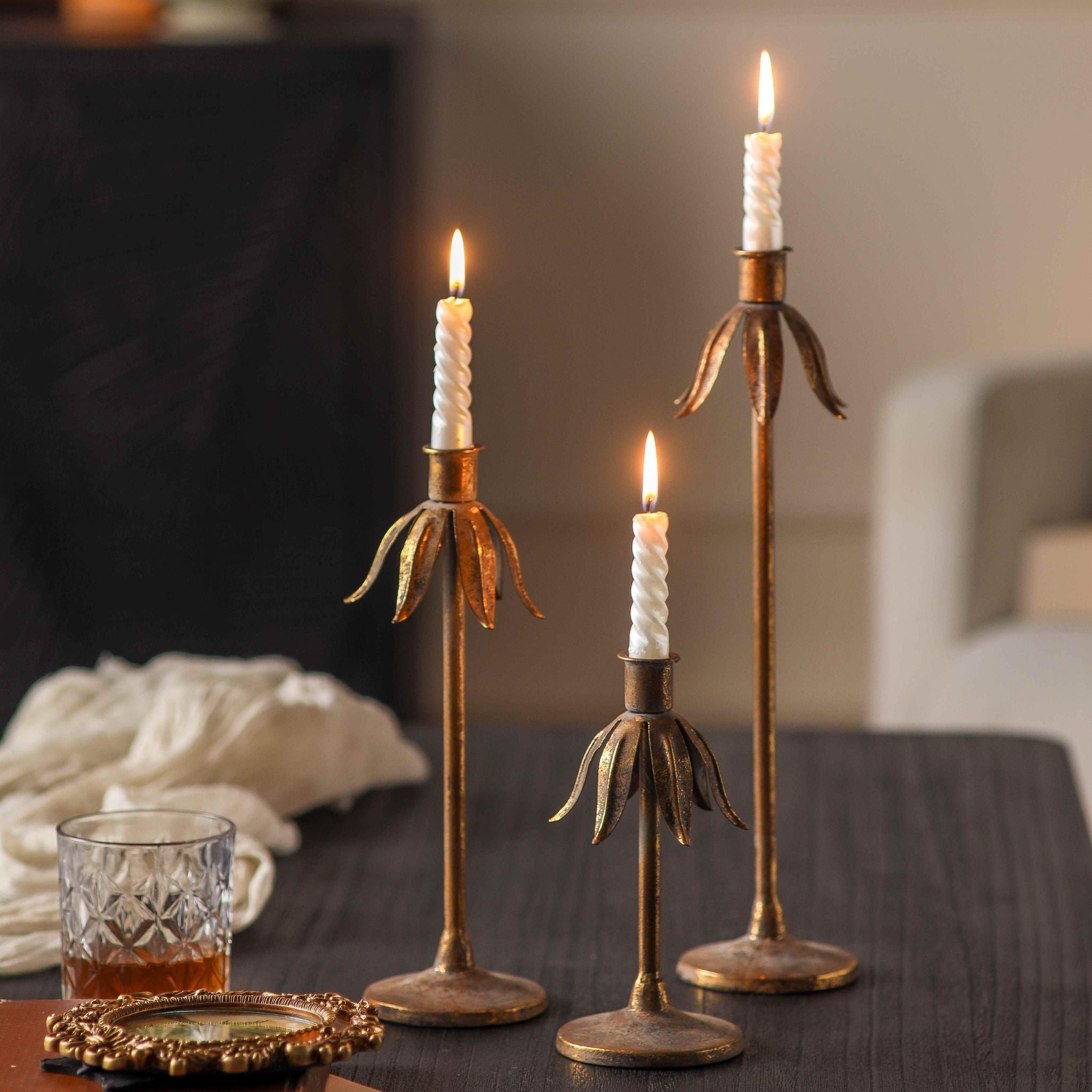 Ines flower candle holder set of three in aged gold at staggered heights on a table