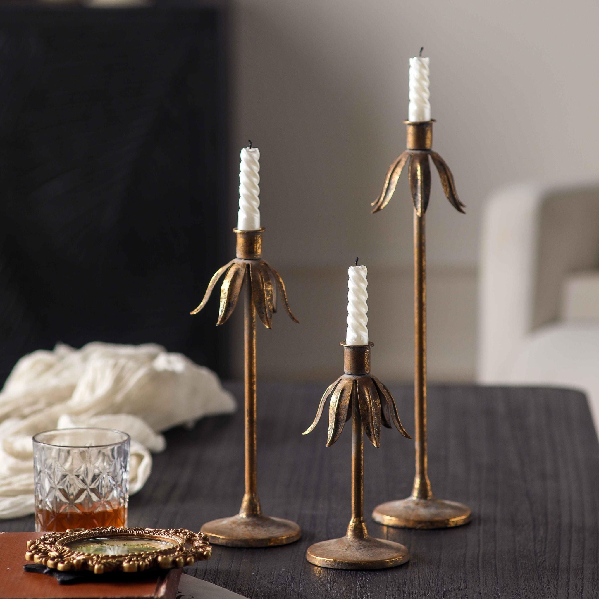 Ines aged gold candle holders with twisted white tapers lit at dusk
