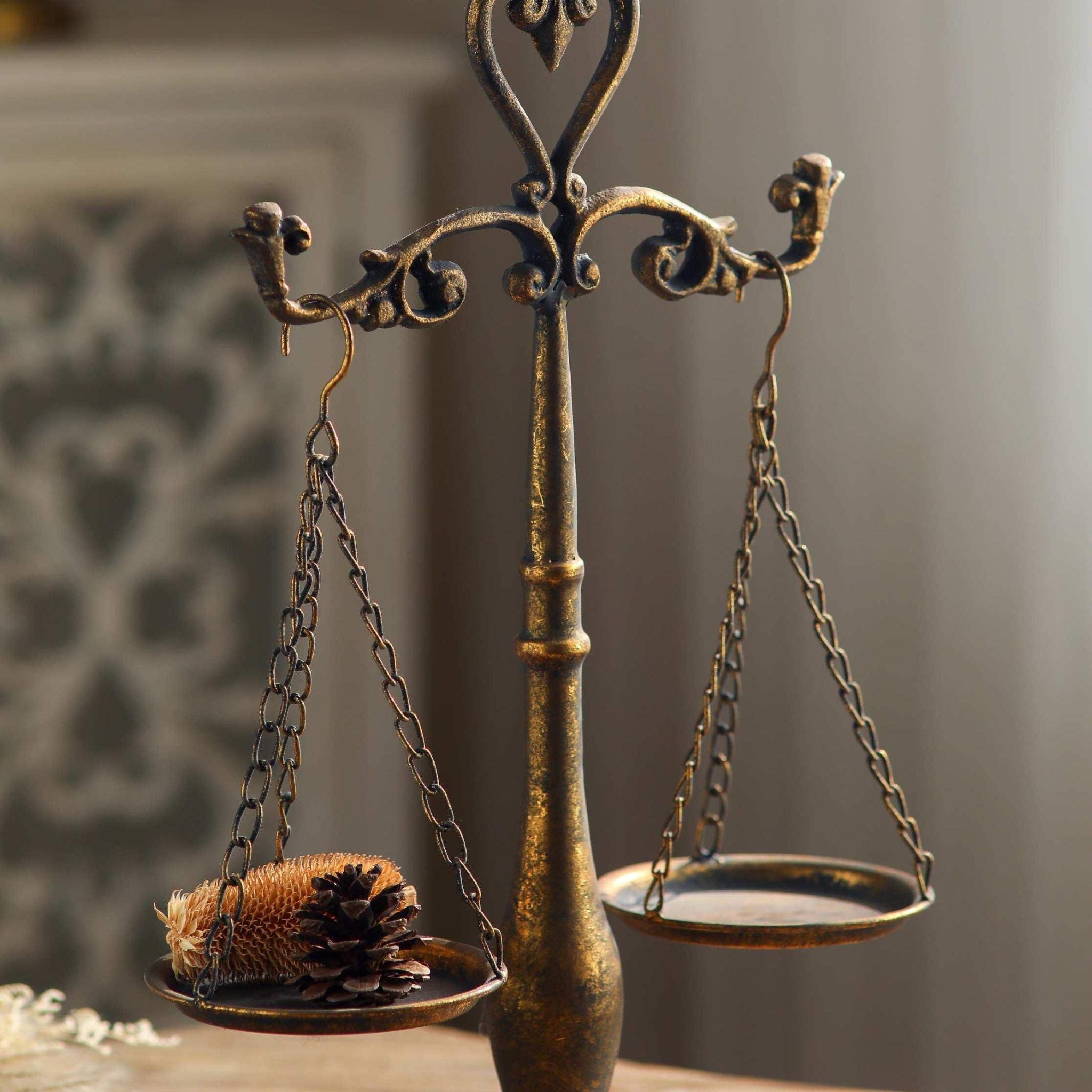 Nimes aged gold balance scales with a pinecone resting in one hanging dish